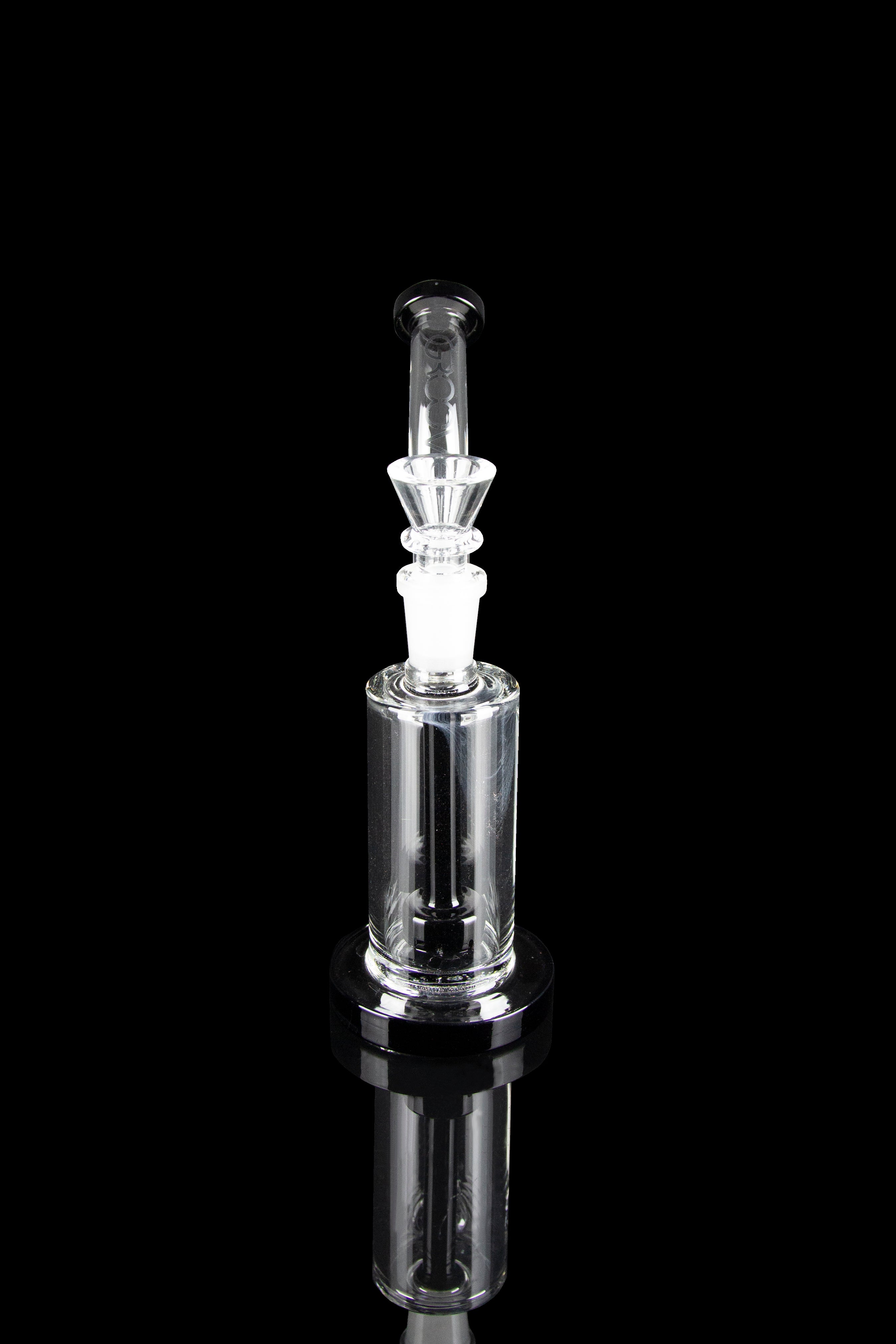 Clear glass dab rig with intricate percolator, reflecting on a black surface.
