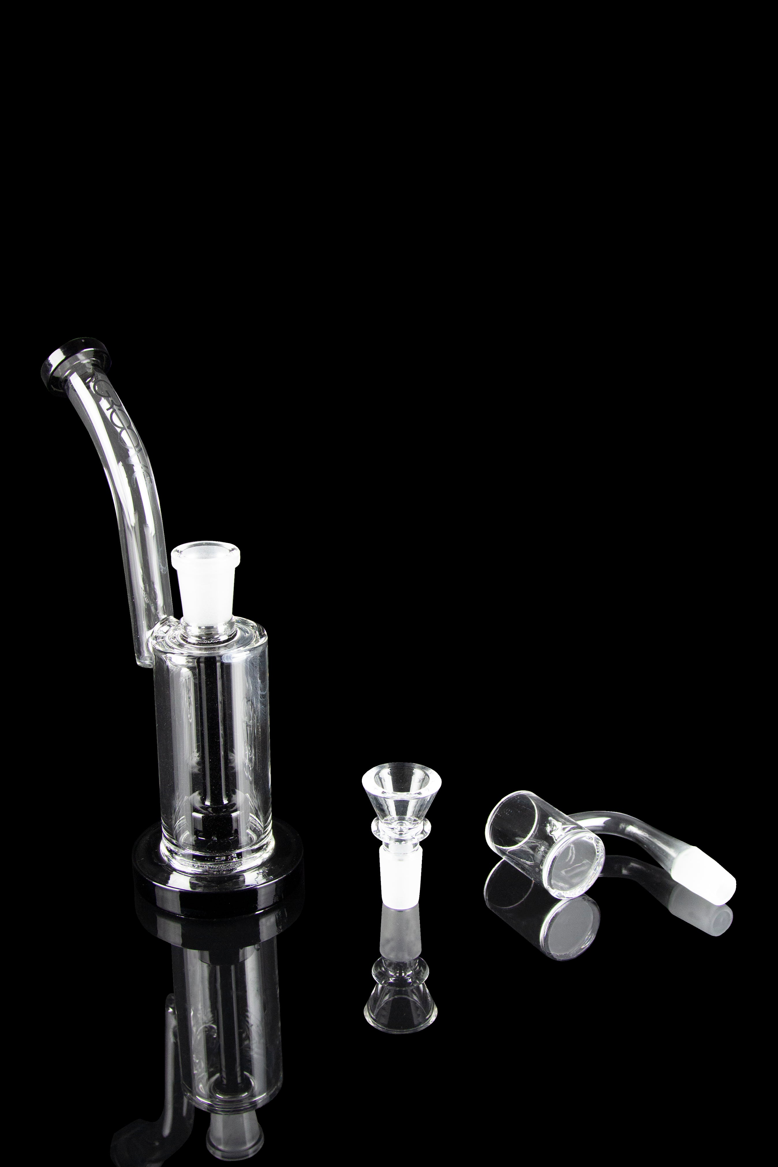 Clear glass bubbler and attachments on a black reflective surface.