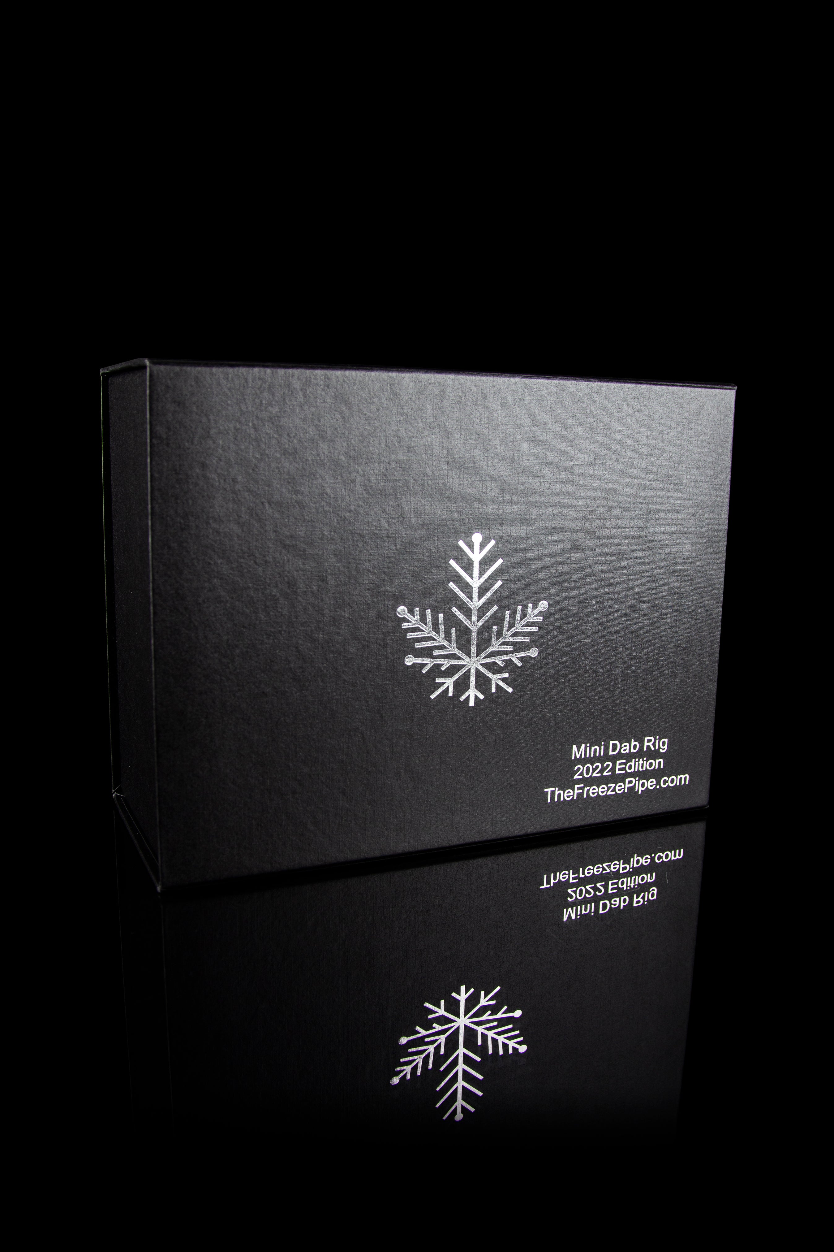 Black box for a cannabis mini dab rig, featuring a snowflake design and website address.