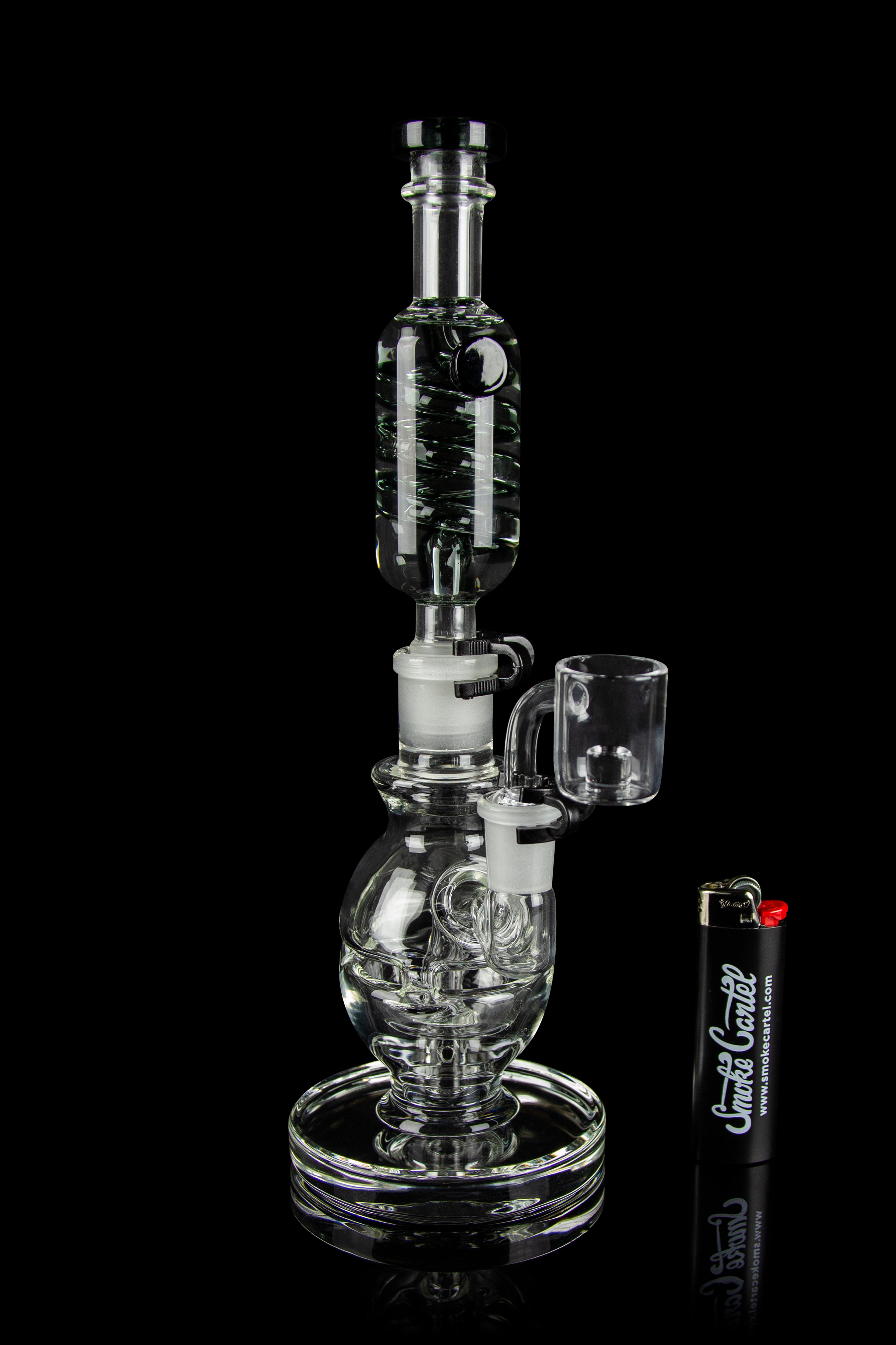 Clear glass water pipe (rig) with a quartz banger, displayed on a reflective surface.
