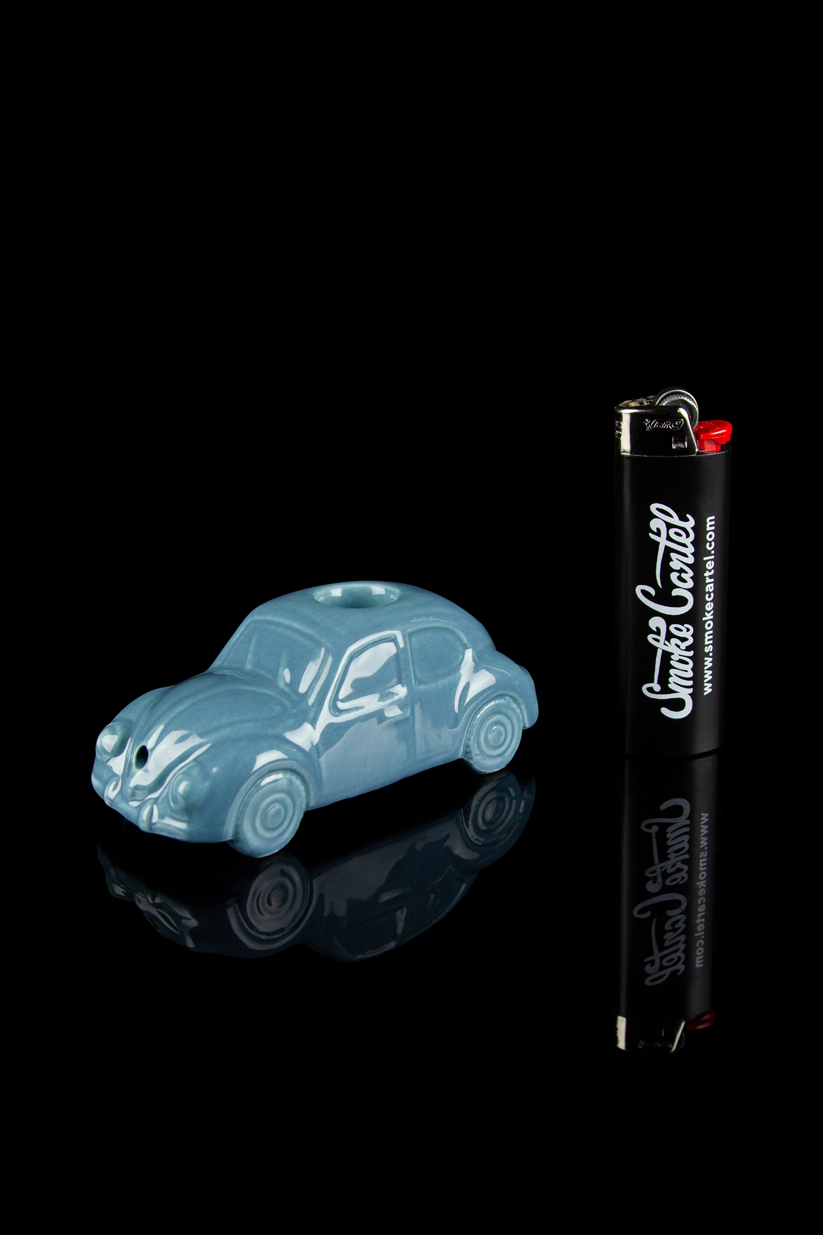 Blue Volkswagen Beetle-shaped cannabis pipe with a lighter beside it, against a black background.