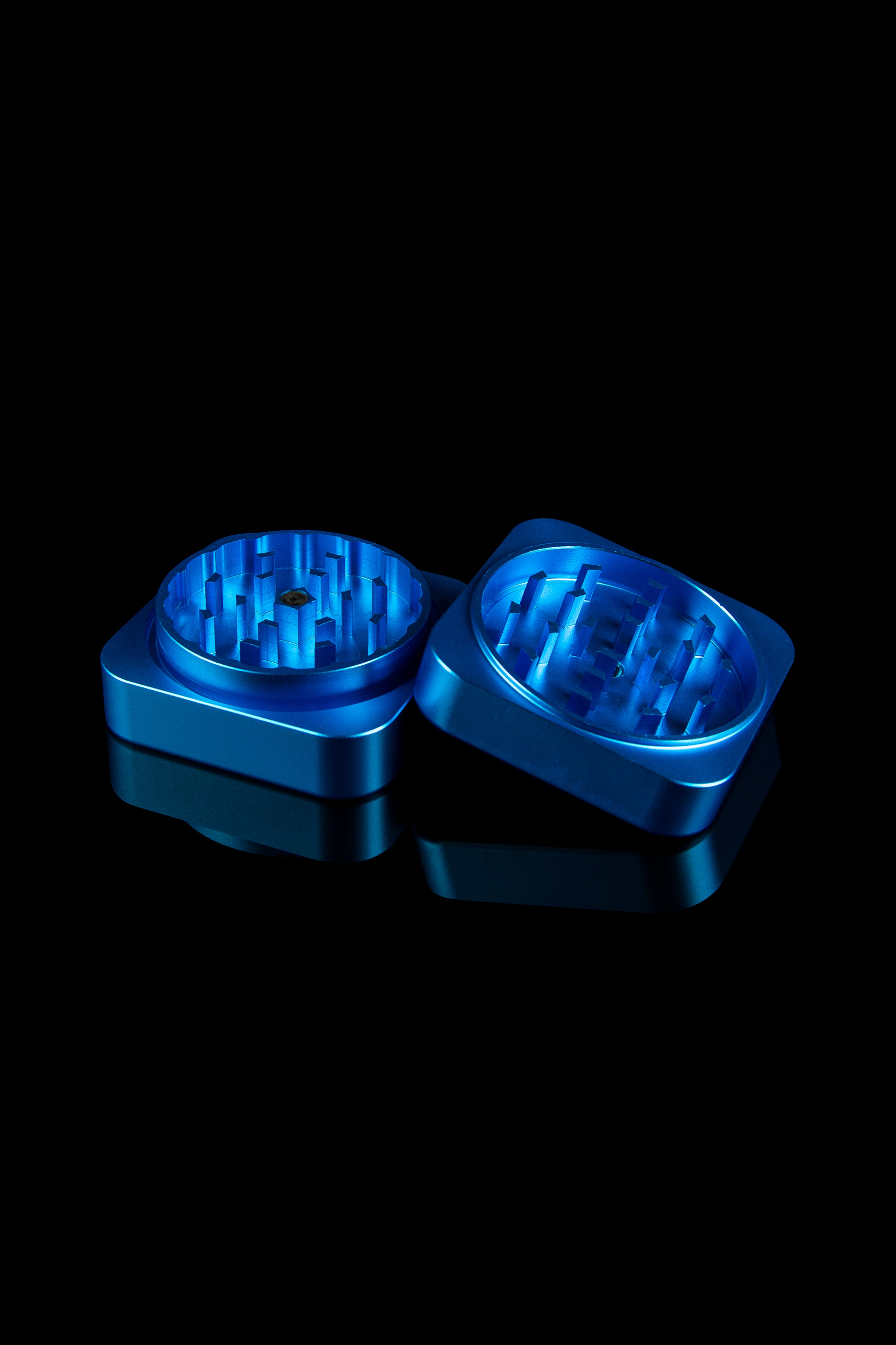 Blue metal cannabis grinder, open to reveal the internal grinding mechanism, against a black background.