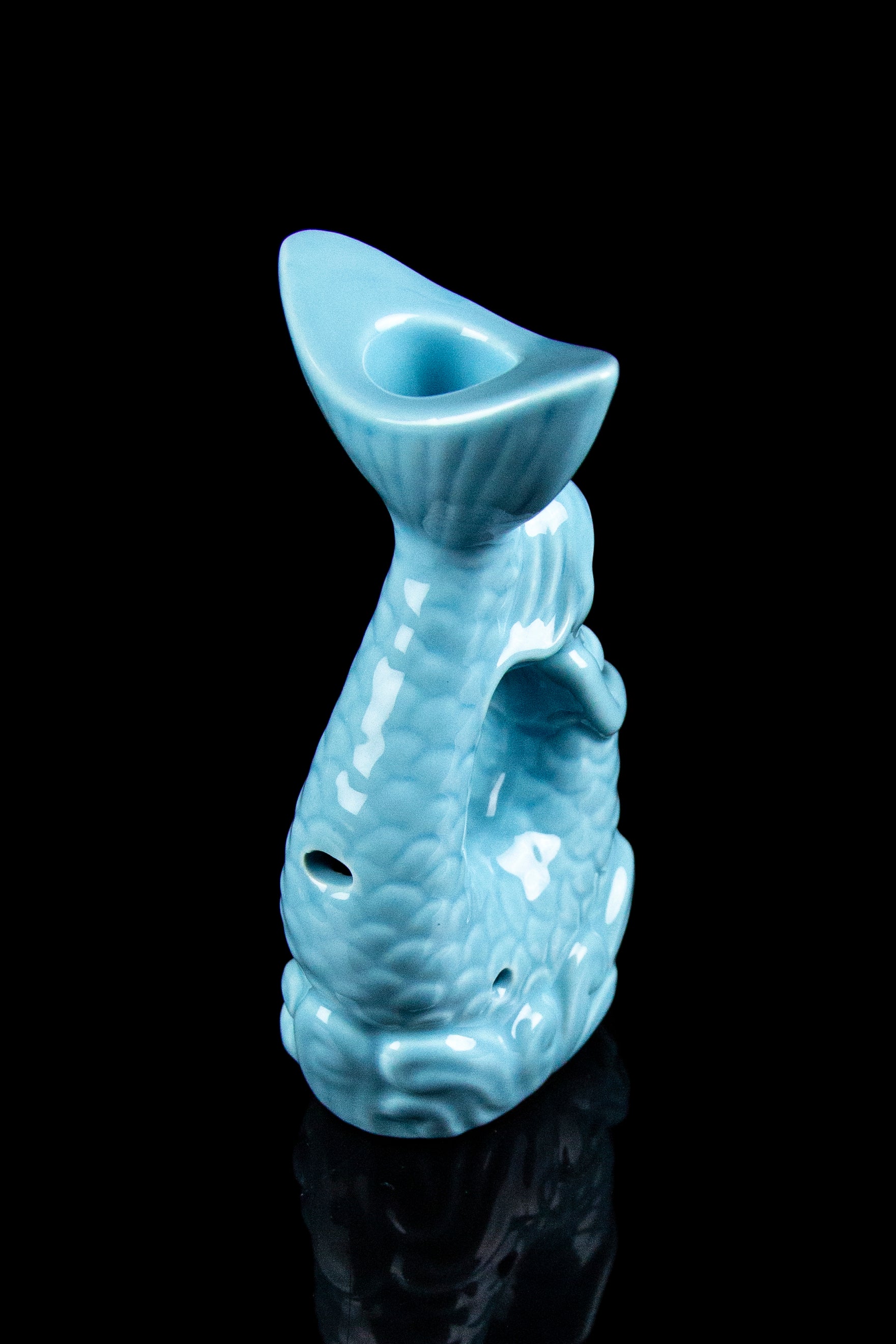 Ceramic water pipe shaped like a fish, turquoise glaze, against a black background.