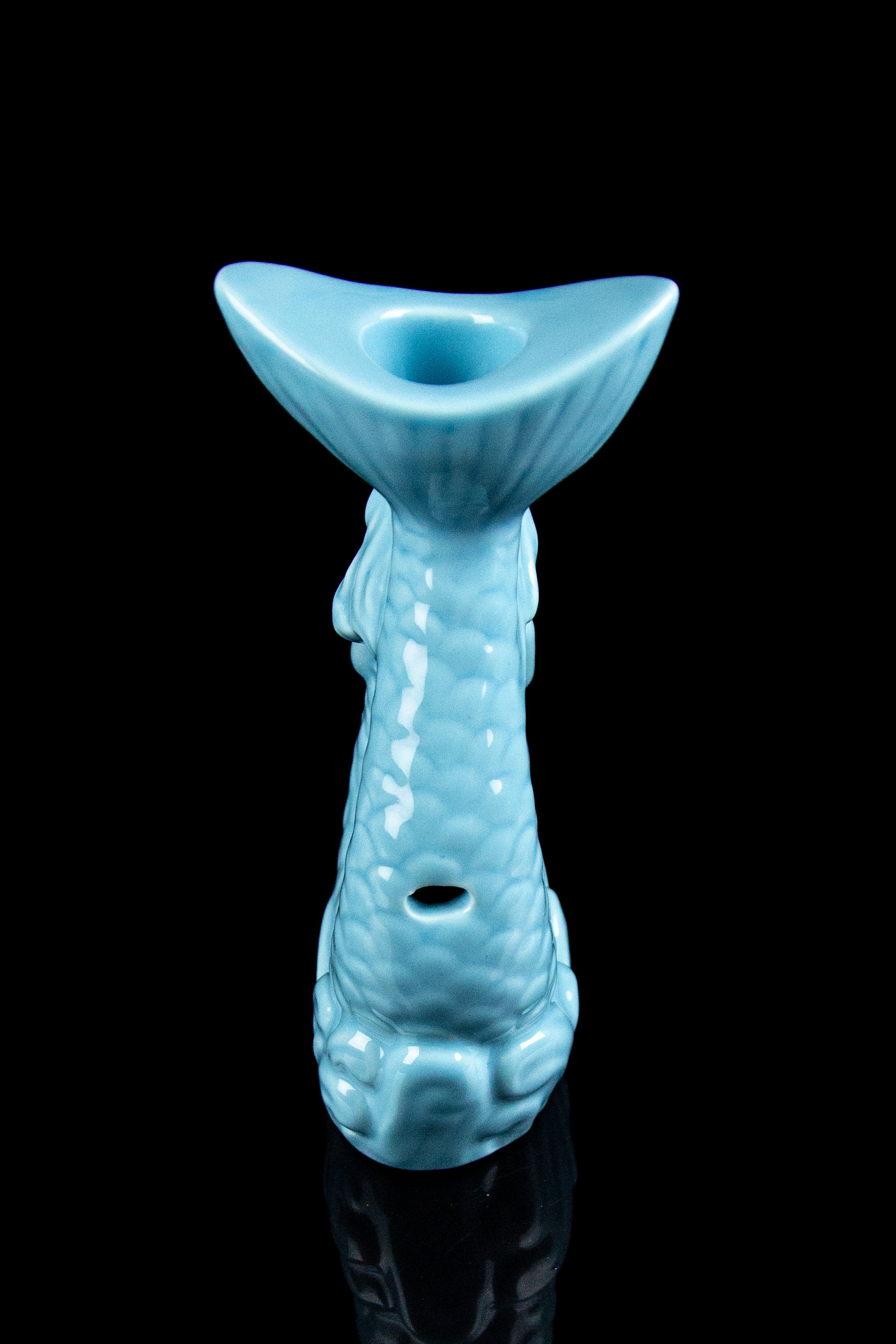 Ceramic cannabis water pipe shaped like a tiki statue, turquoise glaze, black background.