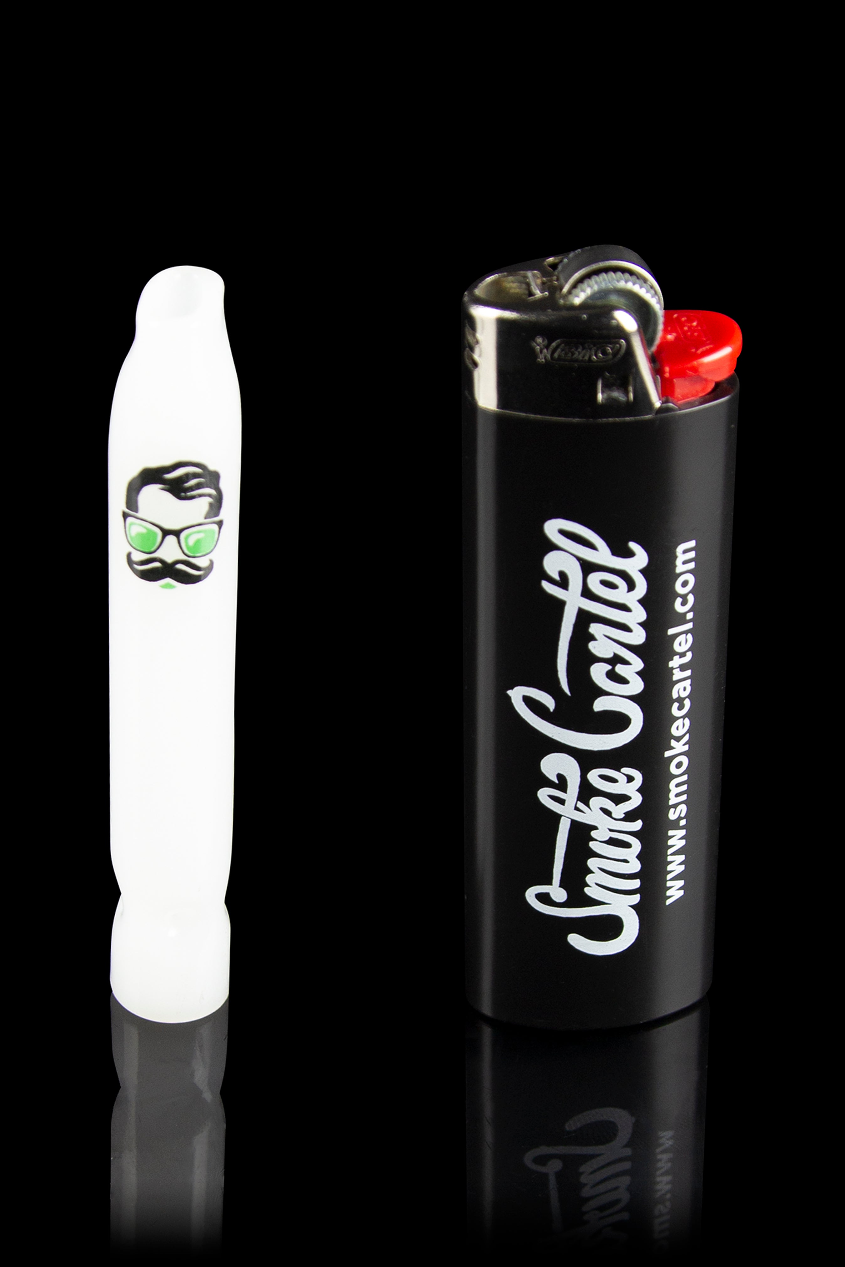White glass pipe with a cartoon face design next to a black lighter branded with “Smoke Cartel” and website address.