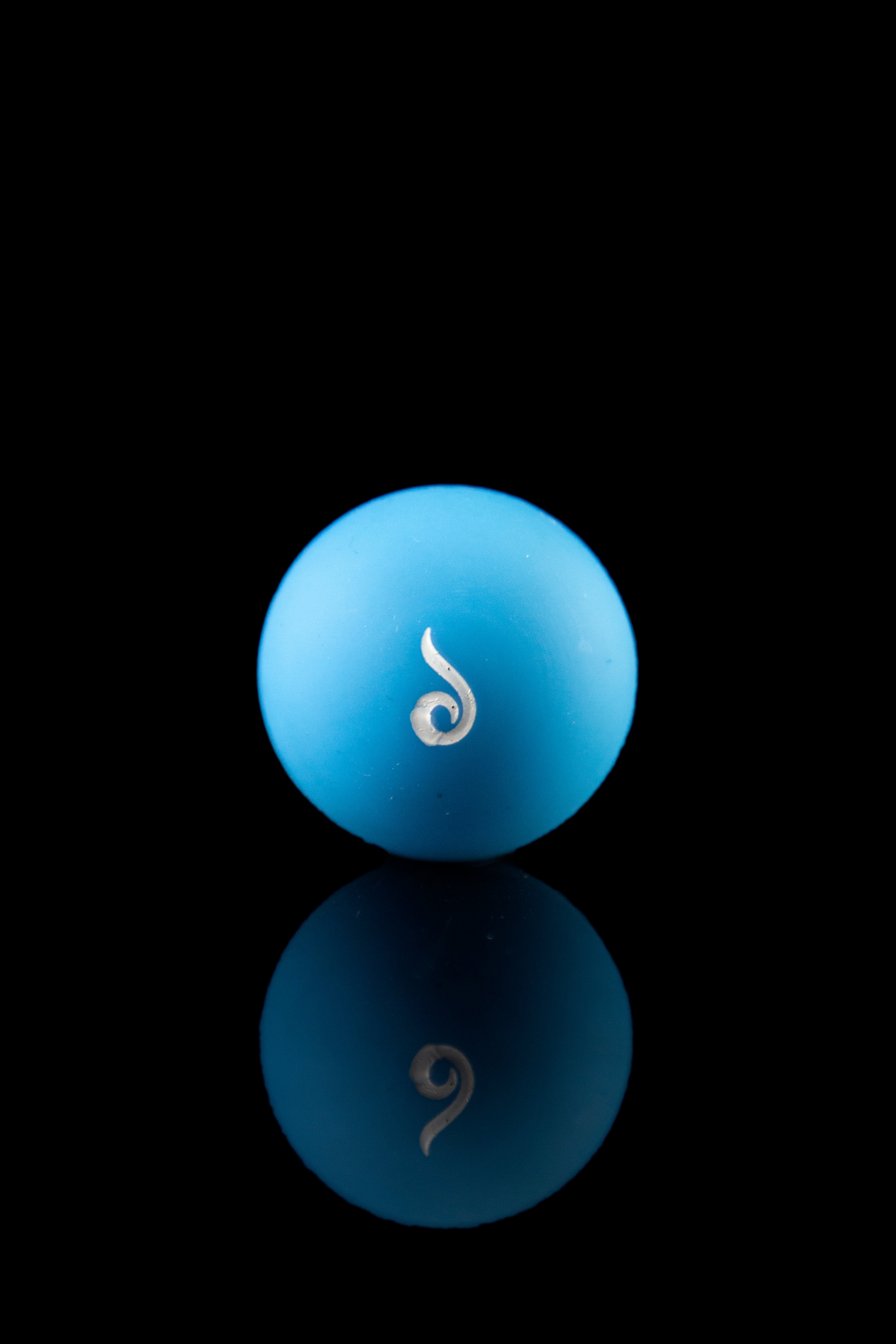 Blue silicone cap with a silver cannabis leaf emblem, reflected on a glossy surface.
