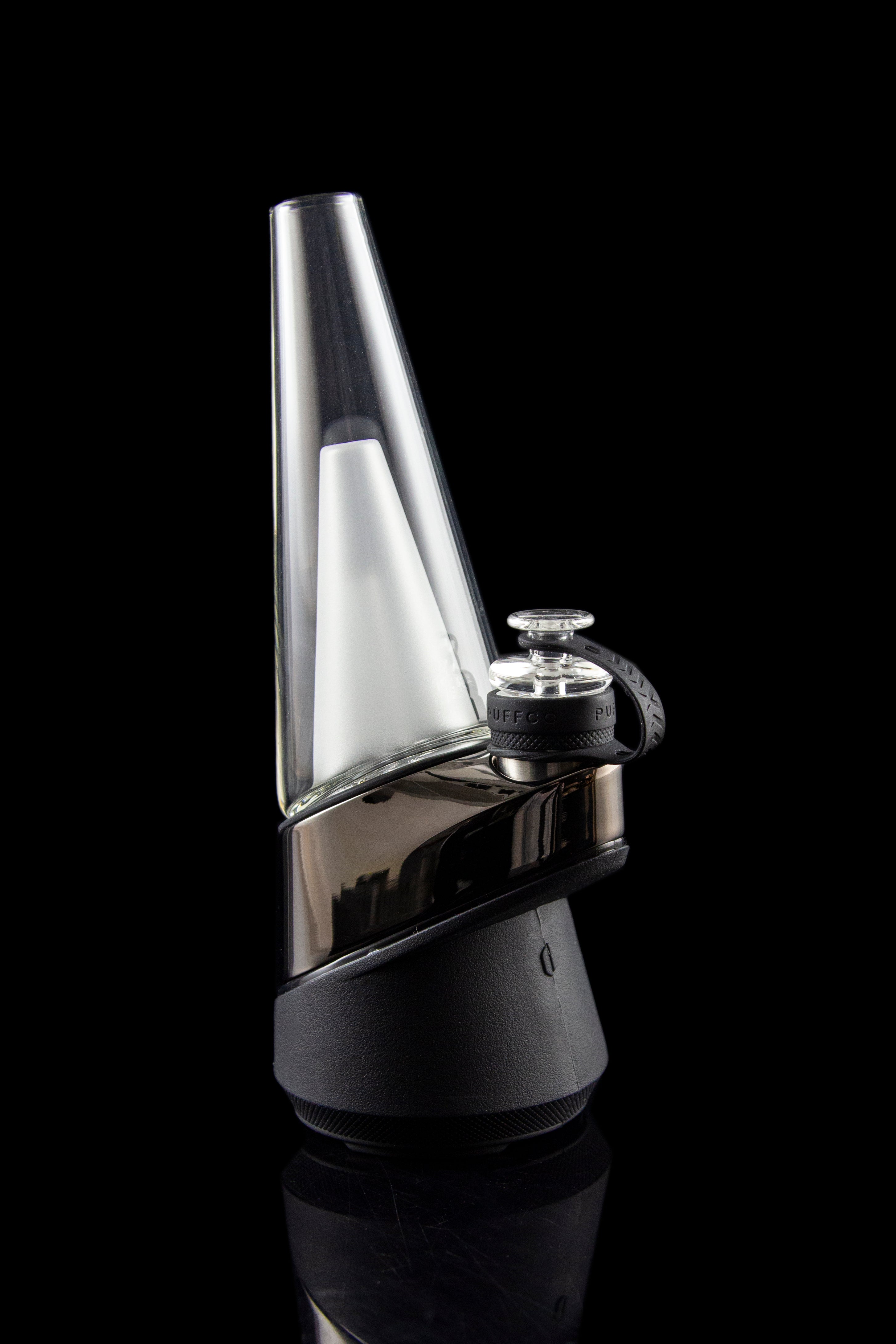 Sleek, black and clear glass cannabis e-rig vaporizer against a dark background.