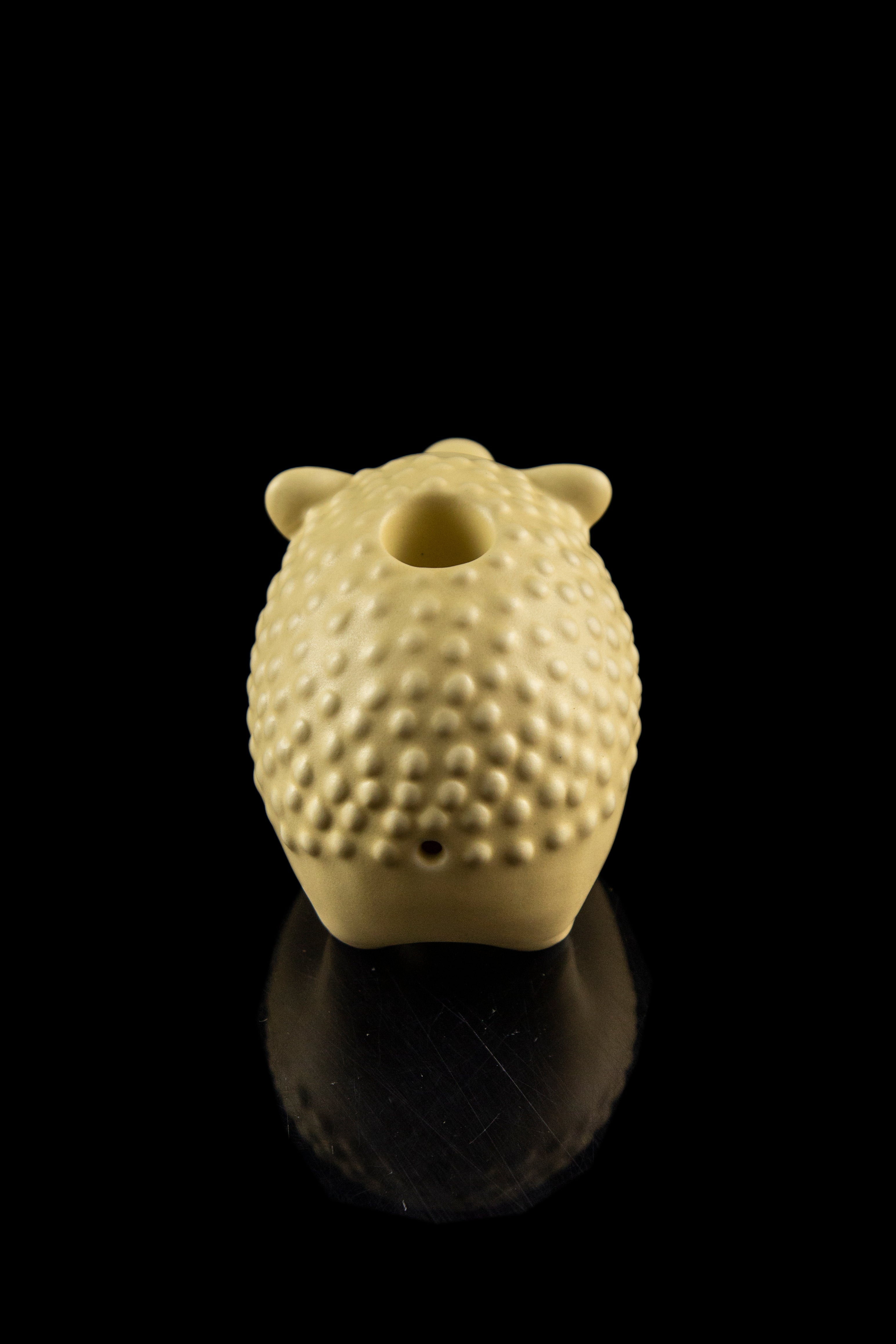 Ceramic cannabis water pipe shaped like a pinecone with visible holes, against a black background.