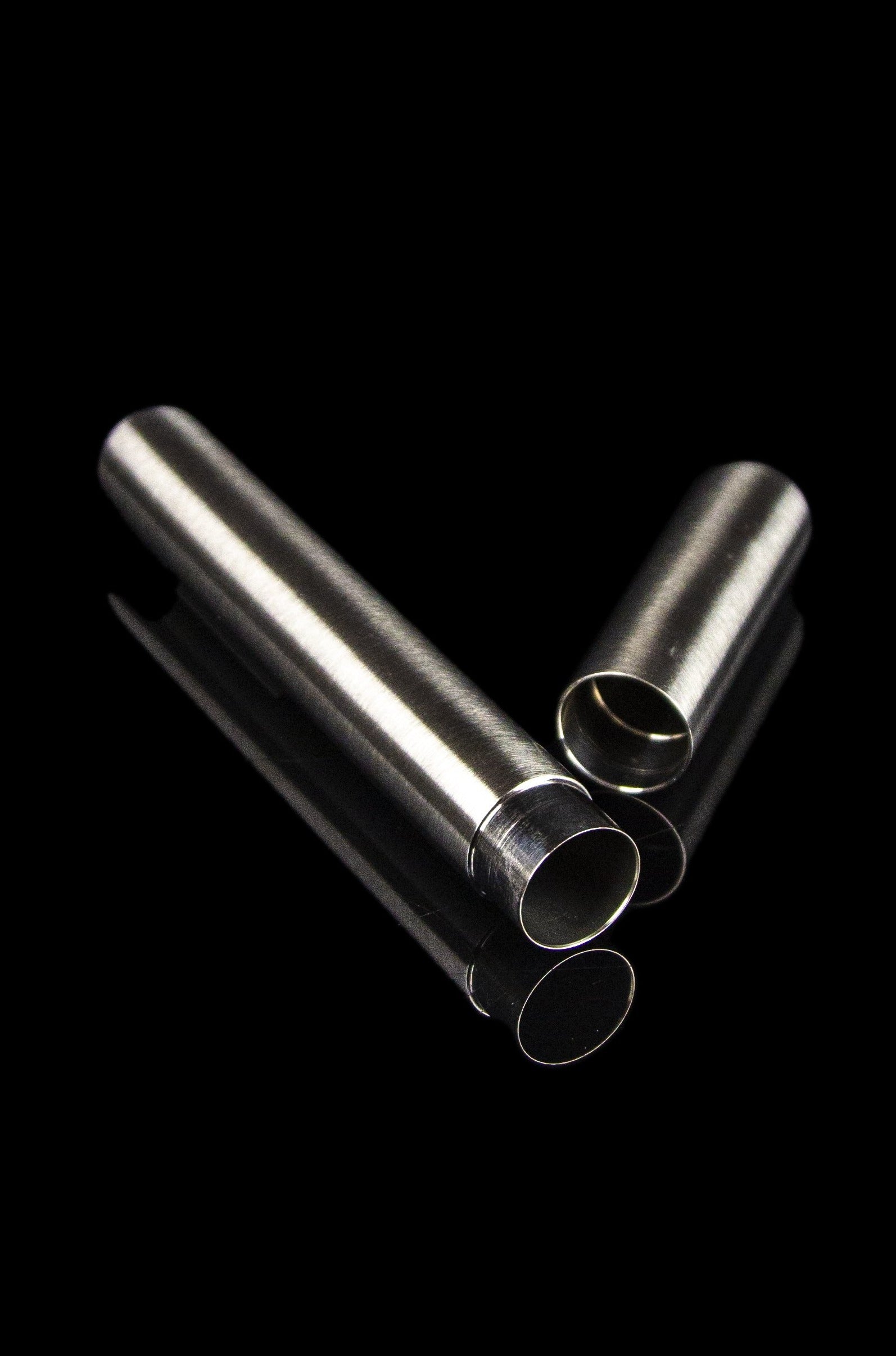 Sleek metal smoking tubes and cylindrical filters against a black background.