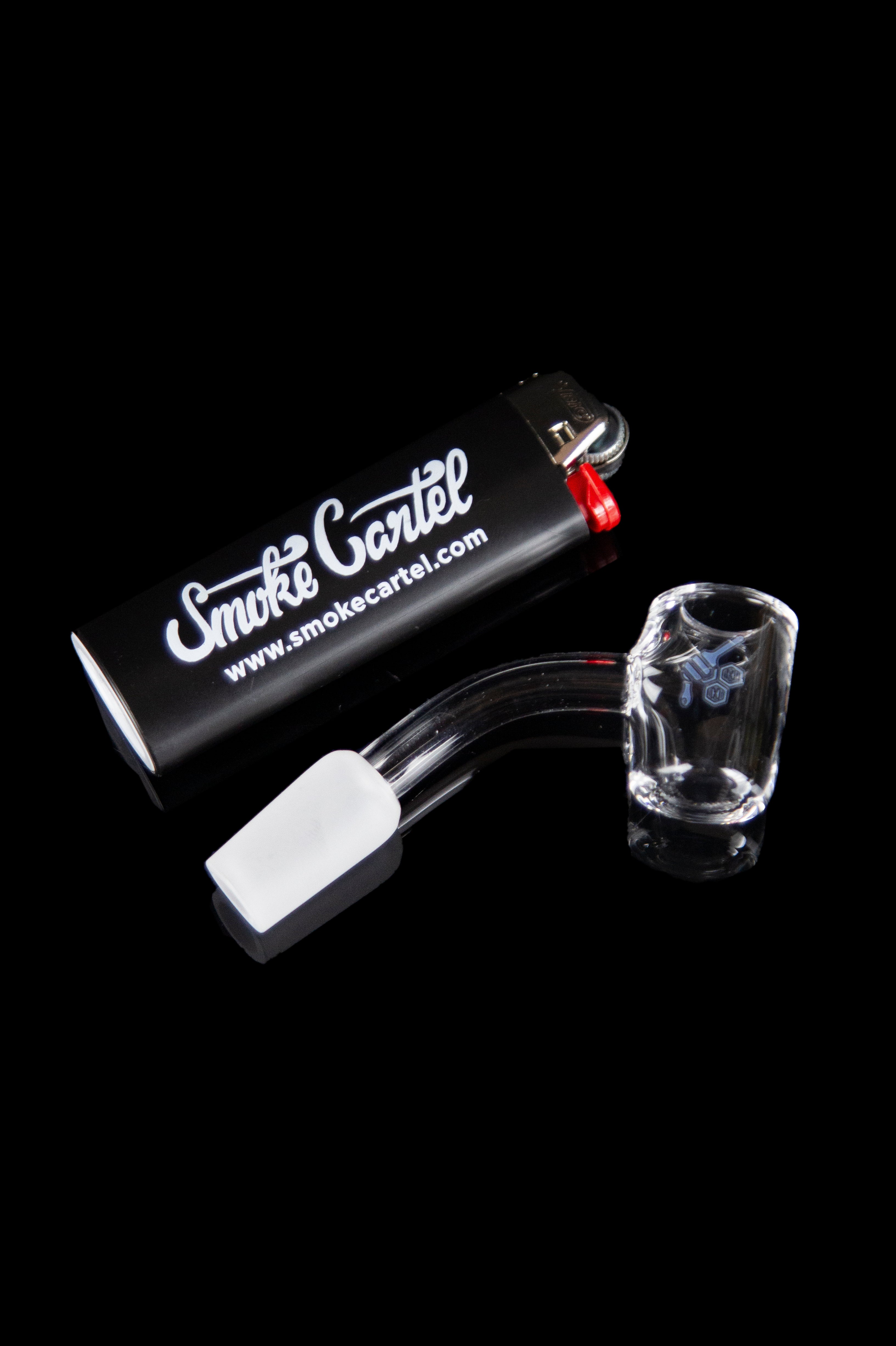 Glass cannabis water pipe with skull design, alongside a glass bowl and lighter, presented on a branded black box.