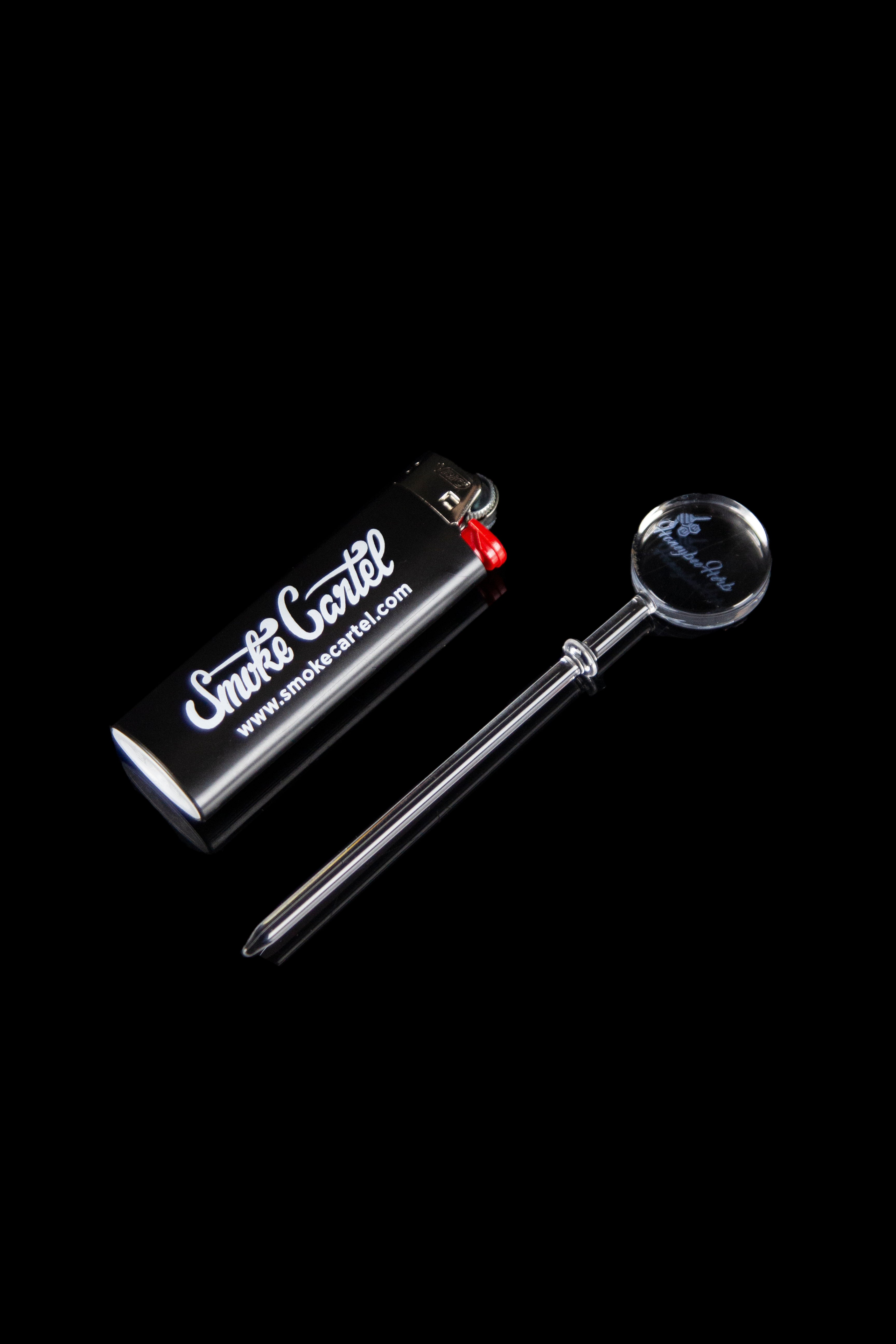 Glass dab tool and butane lighter with "Smoke Cartel" branding on a black background.