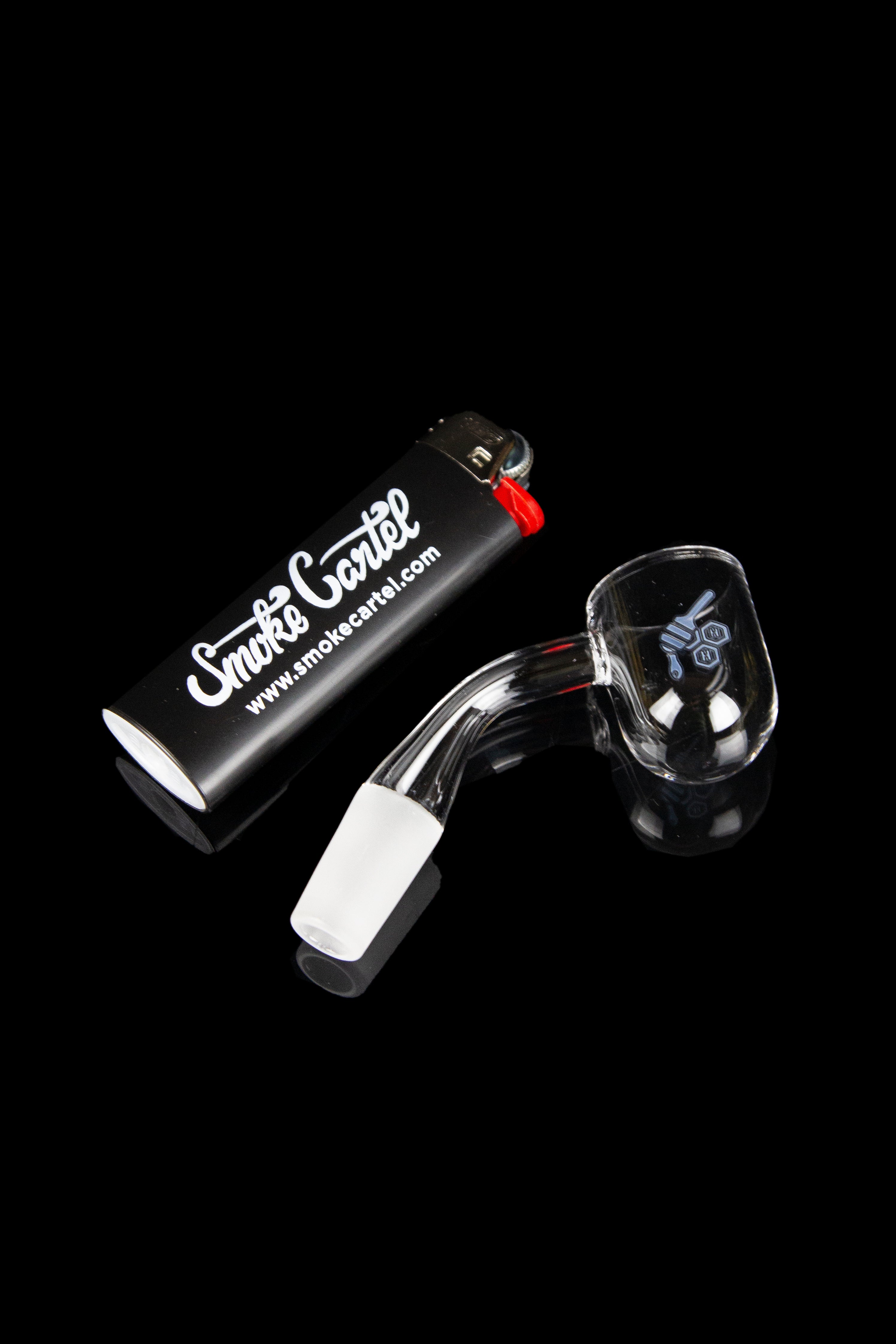 Glass dab rig with a quartz insert and torch lighter on a black surface.