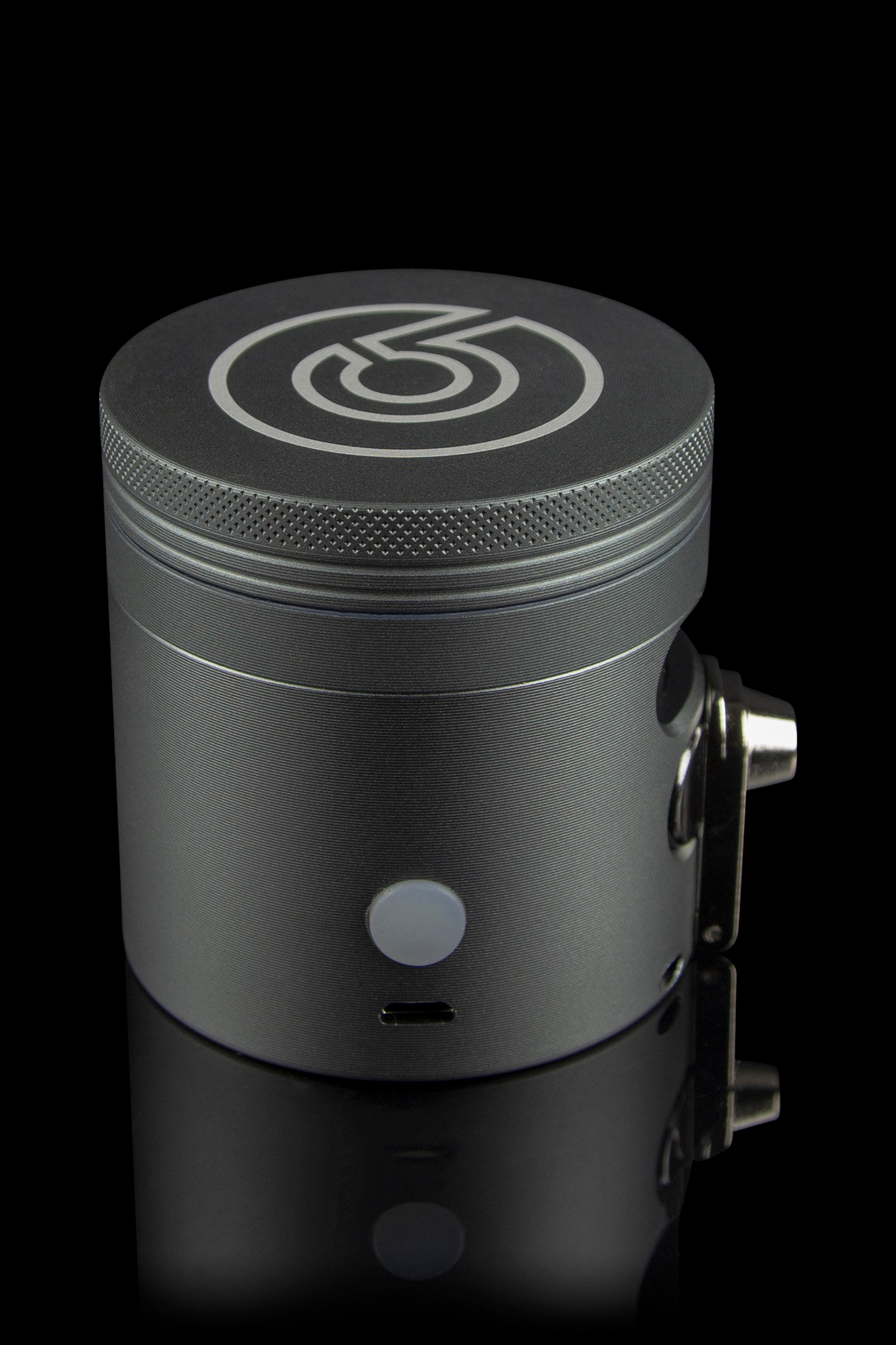 Sleek black cannabis grinder with a branded logo, displayed on a reflective surface.