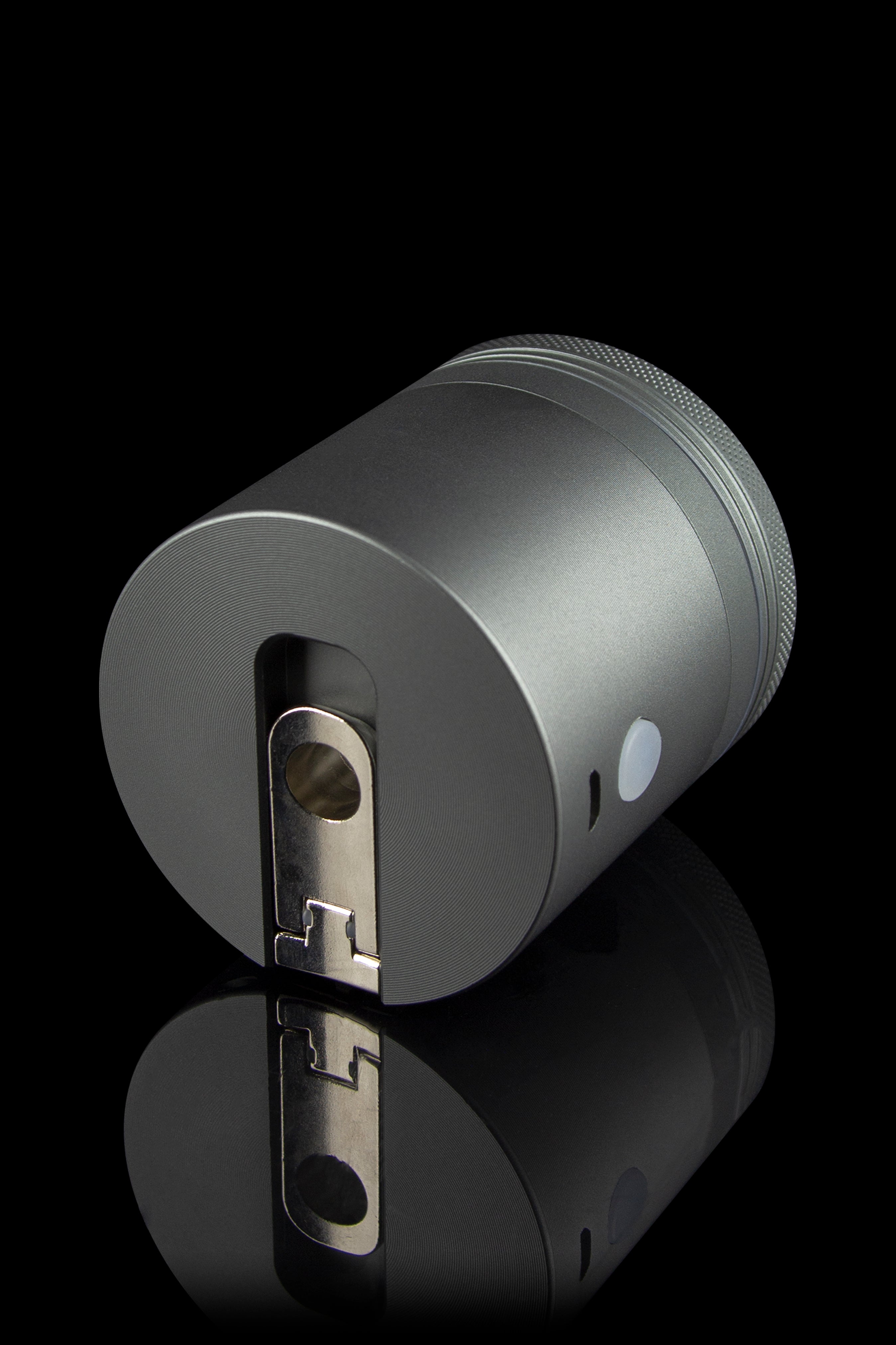 Black cannabis grinder with reflective surface.