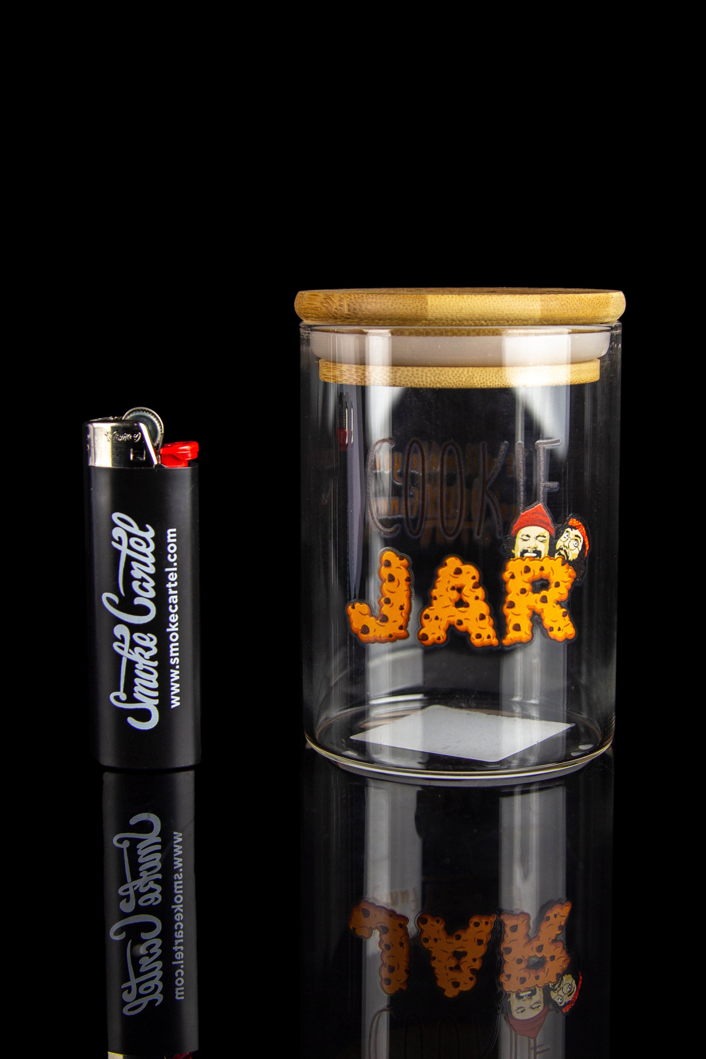 Glass cannabis jar with orange buds and a branded lighter, displayed on a reflective surface.