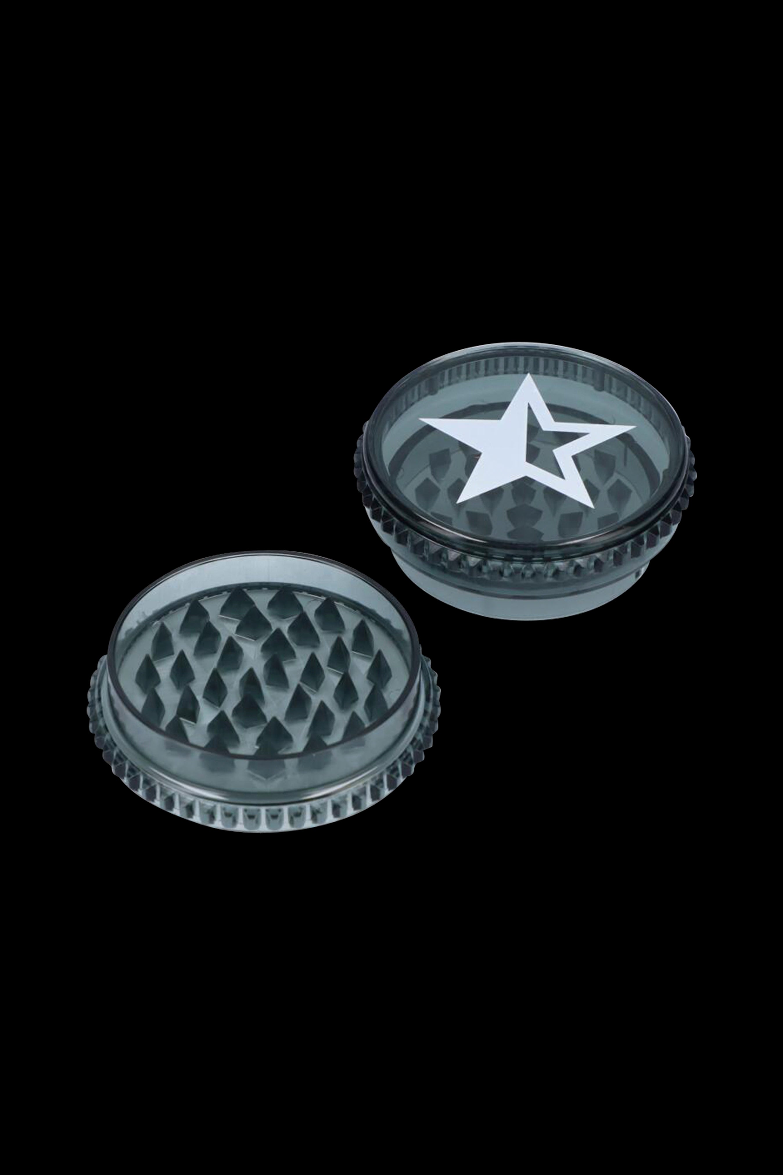 A disassembled, translucent green cannabis grinder with a white star emblem on the lid, shown against a black background.