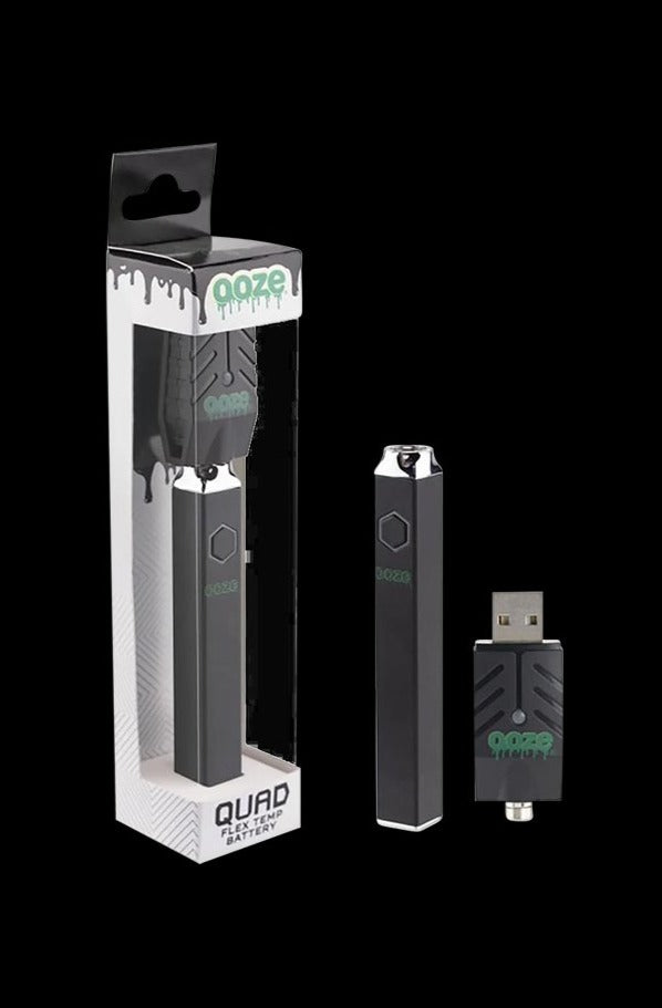 Centered studio shot of the Ooze Quad Flex Temp Vape Pen 510 Battery in rainbow finish standing upright next to its USB charger and retail box on a black background
