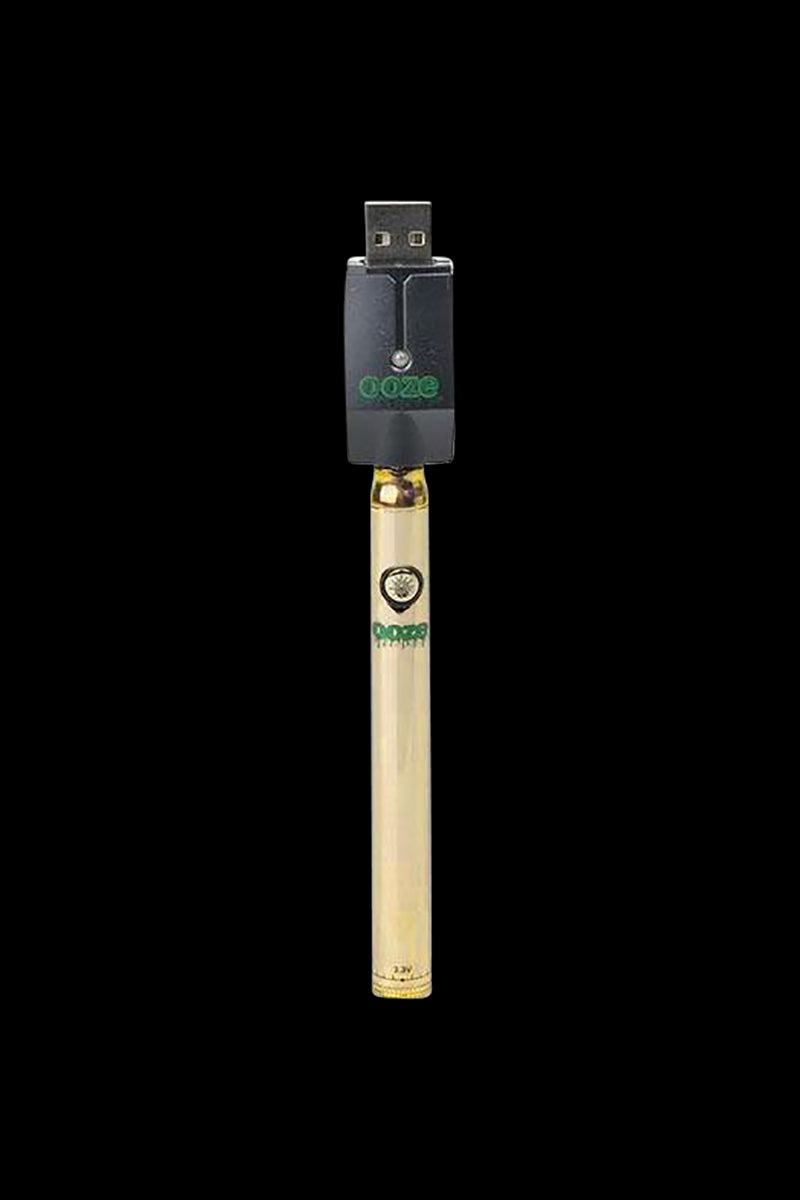 Centered vertical product shot of the Ooze Slim Twist Battery with Charger in teal-accented gold finish against a plain black background