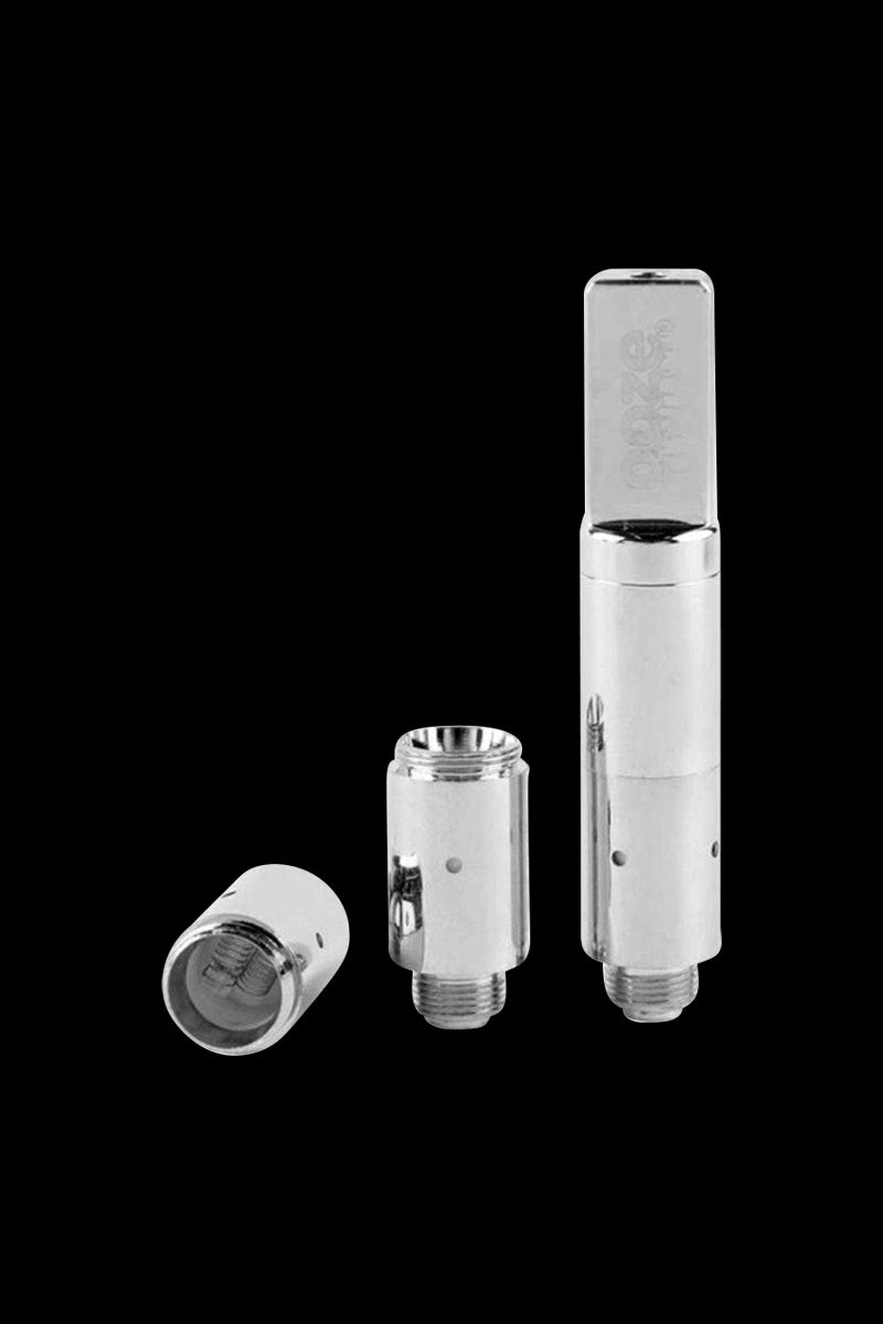 Three-piece studio shot of the chrome Ooze Slim Twist Pro Wax Atomizer Tank standing upright with two disassembled coil components on a black background.