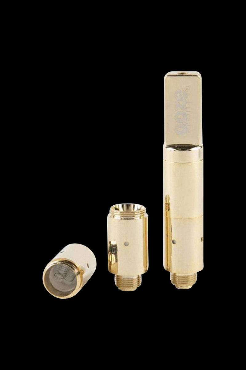 Close-up front view of the gold Ooze Slim Twist Pro Wax Atomizer Tank with two disassembled gold coil sections on a black background.