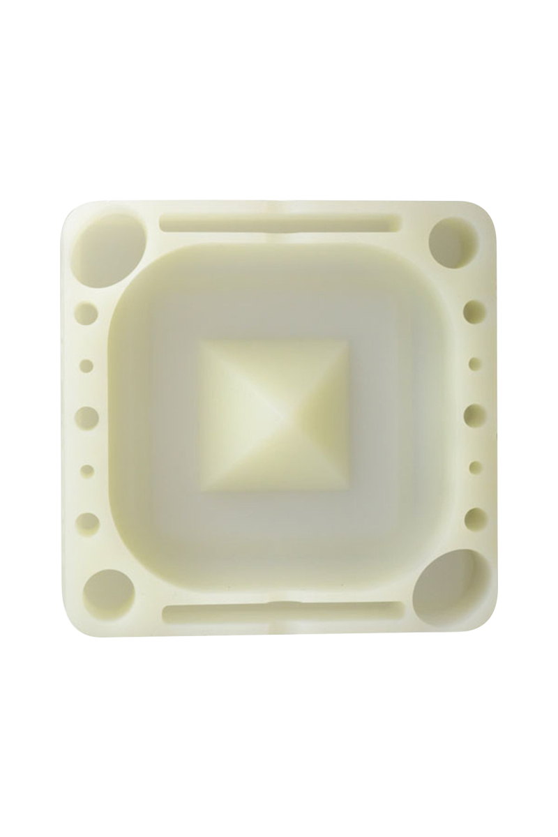 Top-down view of the pale cream Pulsar Tap Tray showing a square recessed center with a raised pyramid and multiple circular and rectangular tool slots around the edges.