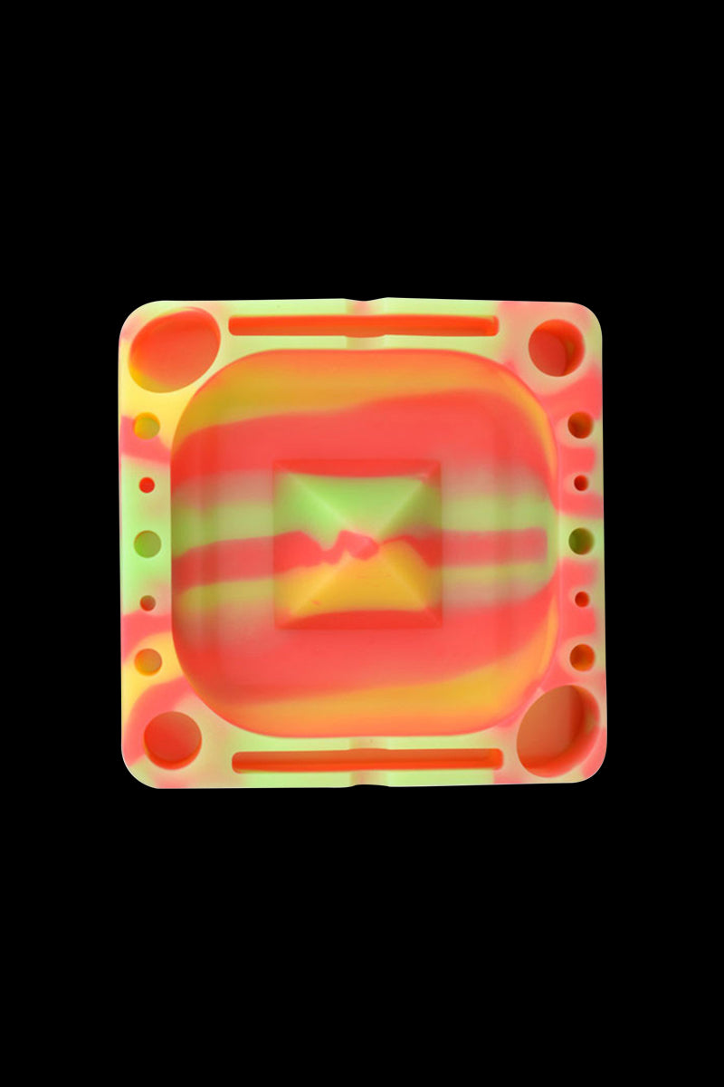 Top-down view of a neon striped Pulsar Tap Tray with rounded square center and multiple circular and sloted compartments on a black background.