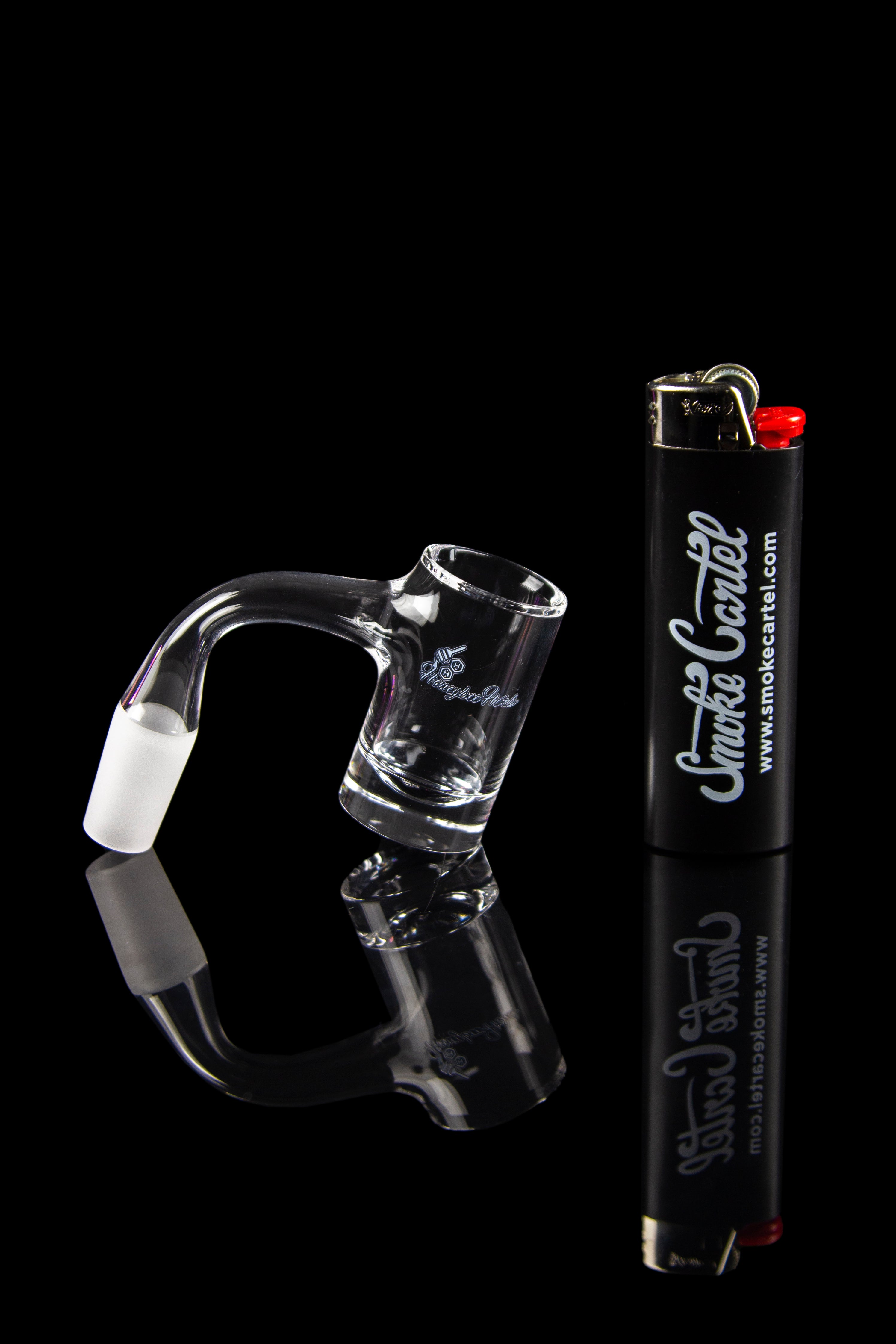 Clear glass dab rig and lighter on a reflective surface.