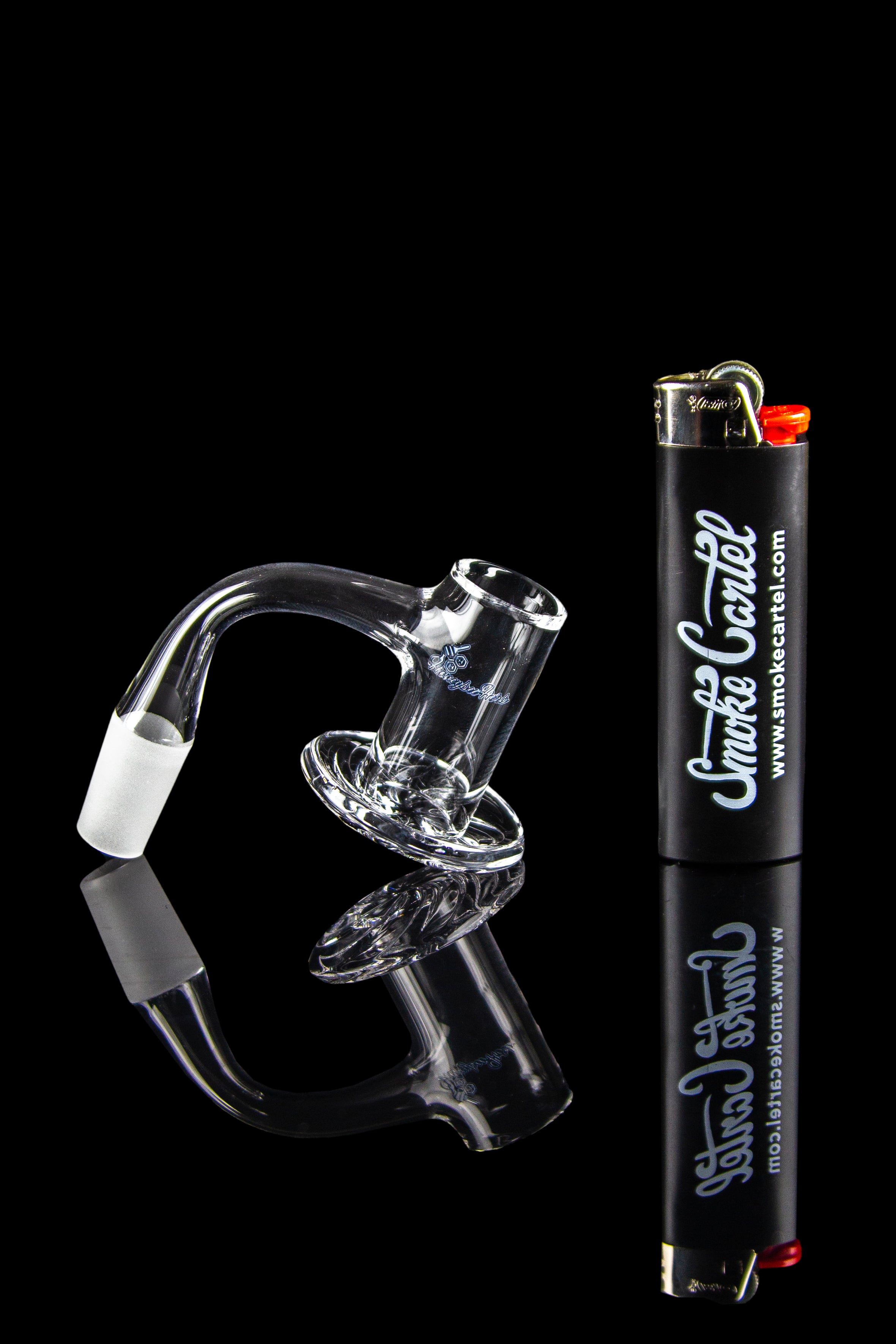 Clear glass dab rig and lighter on a reflective black surface.