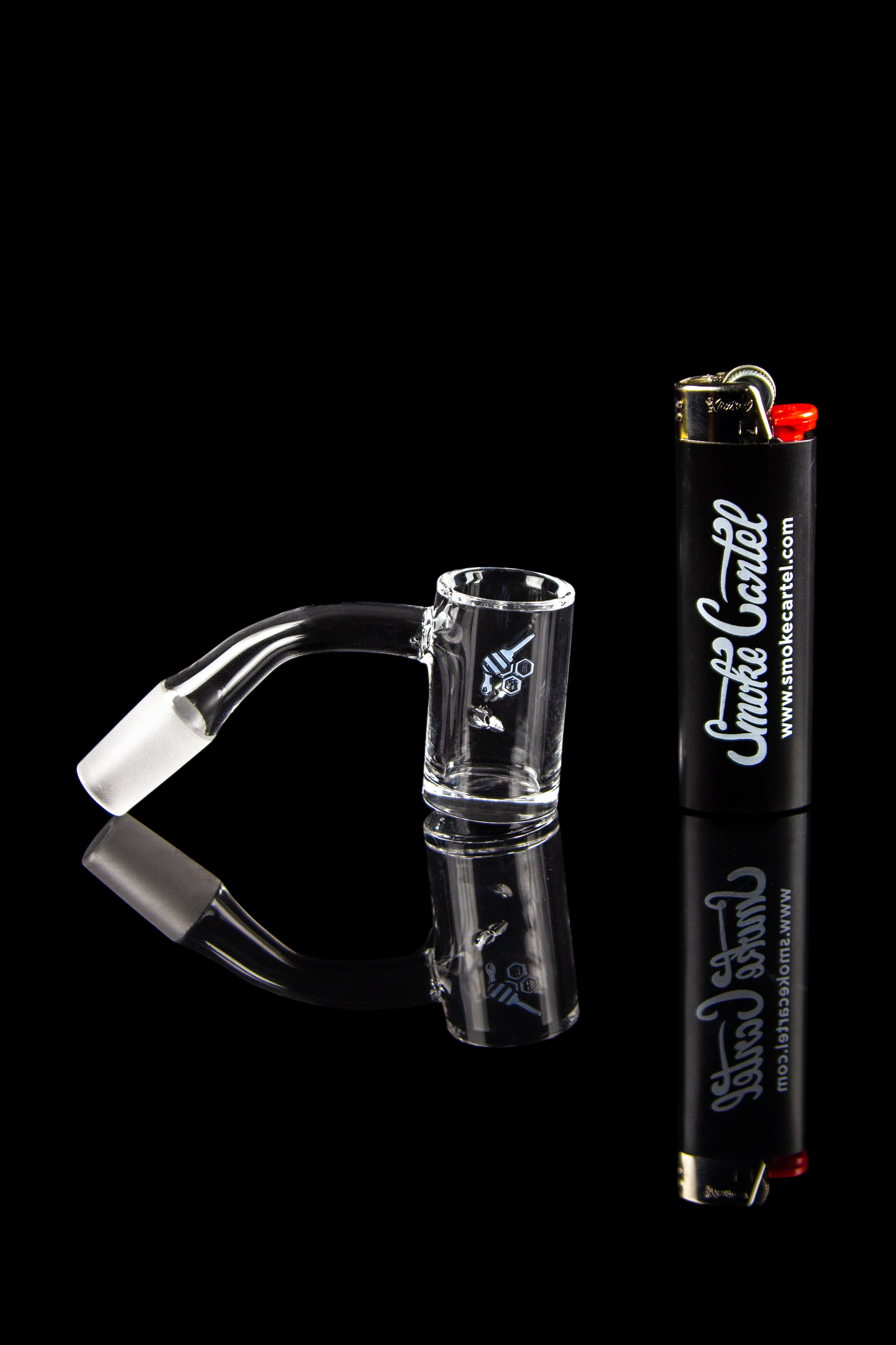 Glass dab rig with a quartz banger and butane torch, reflecting on a black glossy surface.