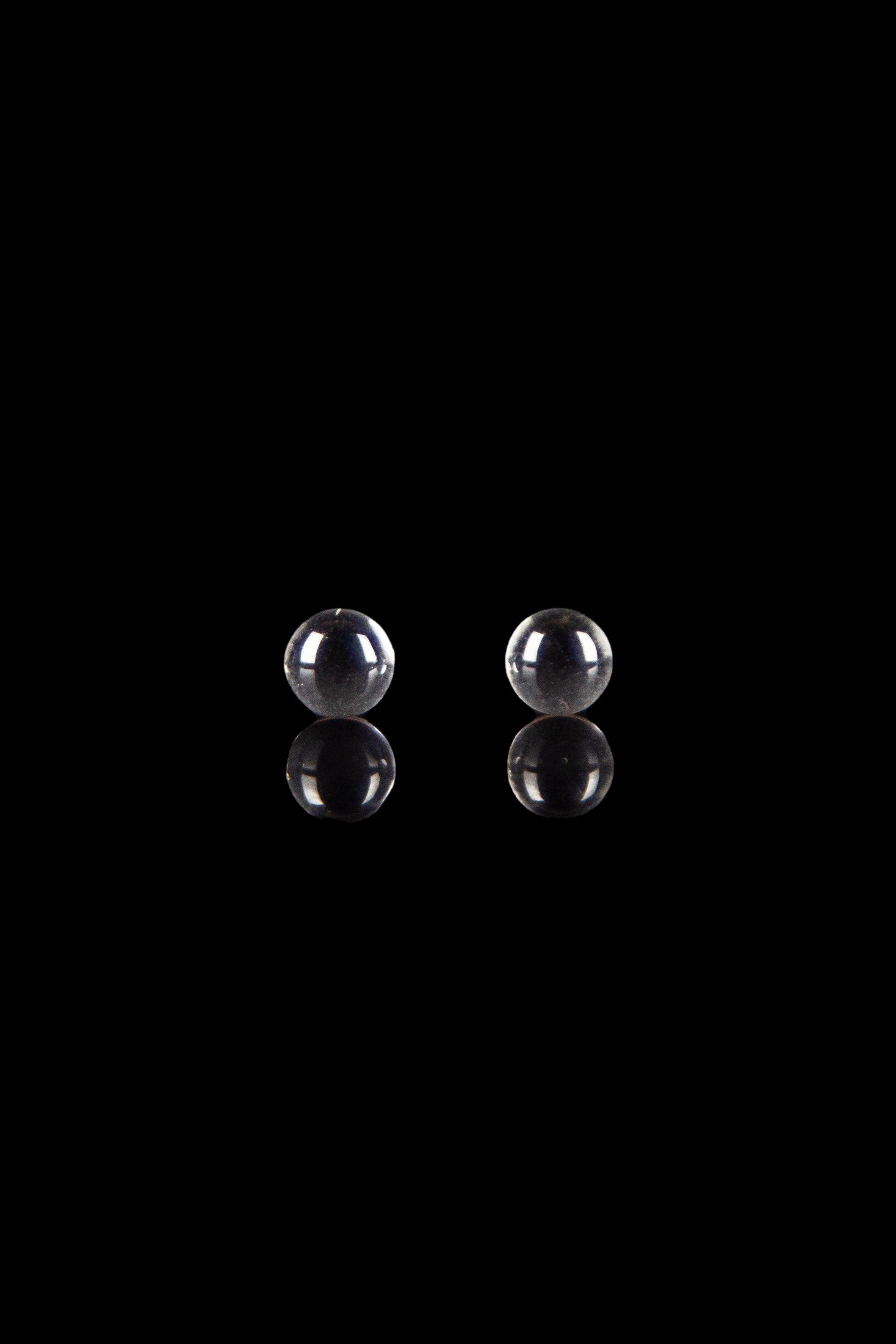 Two glass marbles against a black background, likely for use in a water pipe or dab rig.