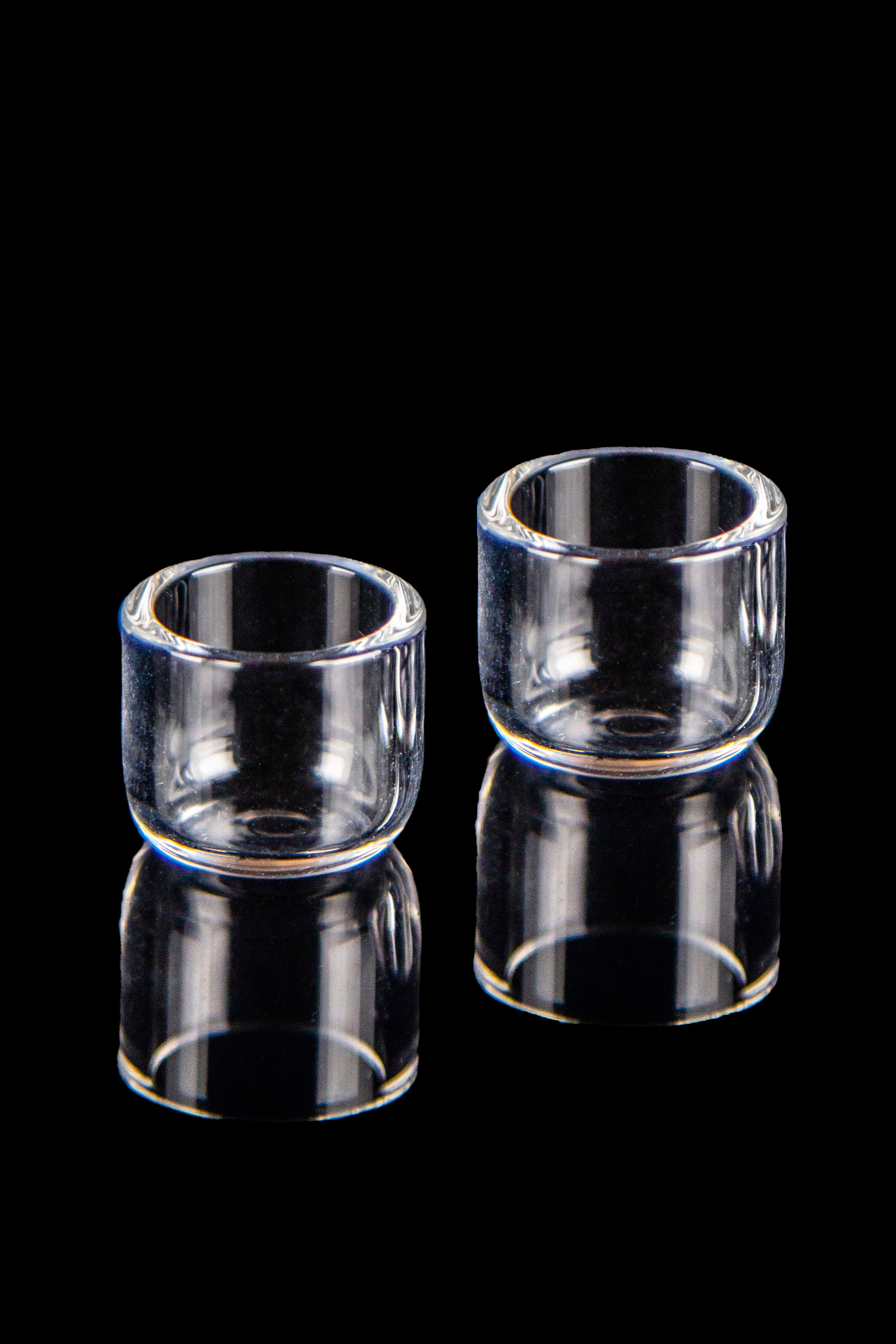 Two clear quartz banger buckets with reflections on a black background.