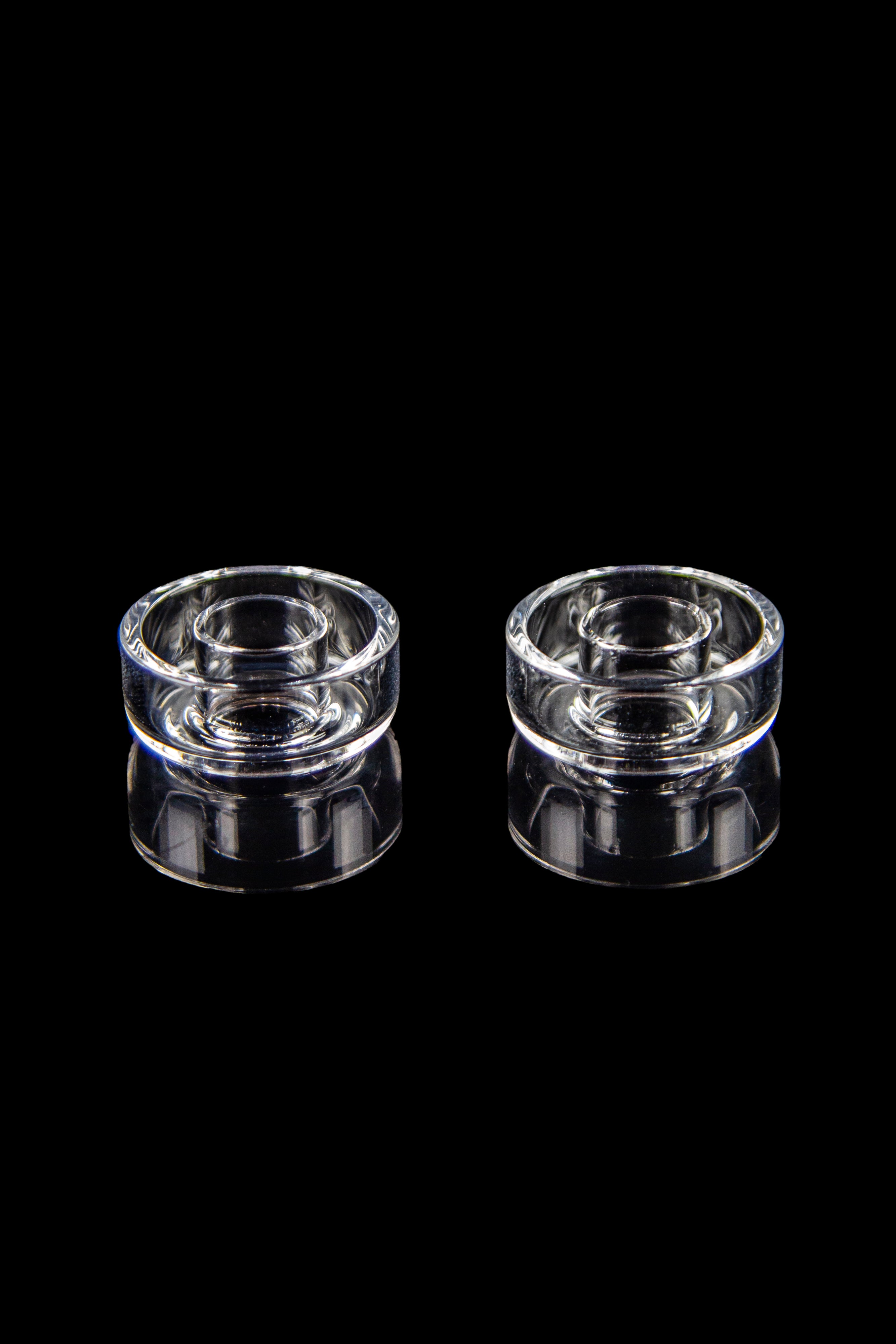 Two clear glass terp pearls for use with cannabis concentrates, isolated on a black background.