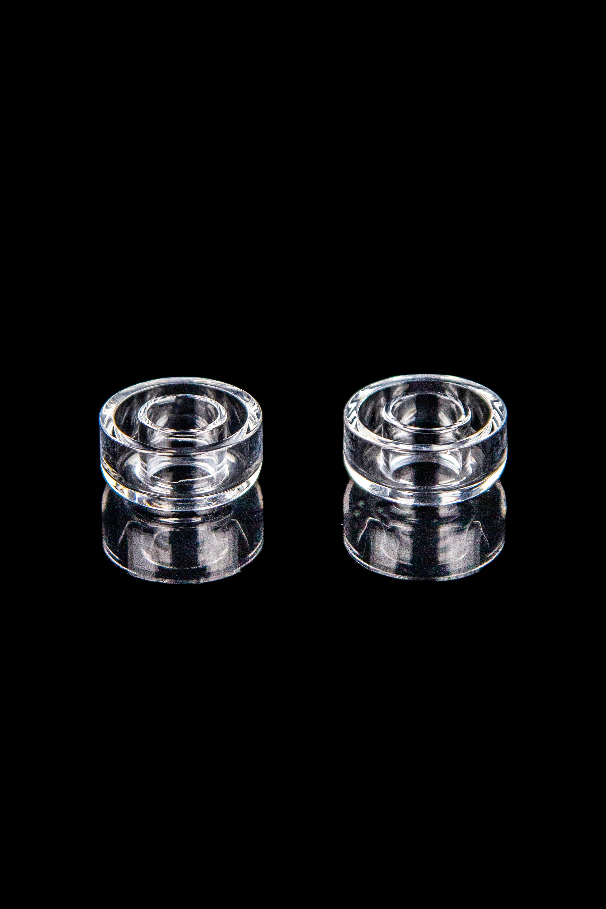 Two clear quartz banger carb caps for cannabis concentrates, isolated on a black background.