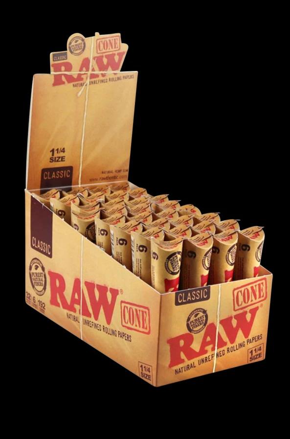 A stack of RAW Natural 1 ¼" Unrefined Pre Rolled Cones is displayed against a dark backdrop, showcasing the branded packaging.