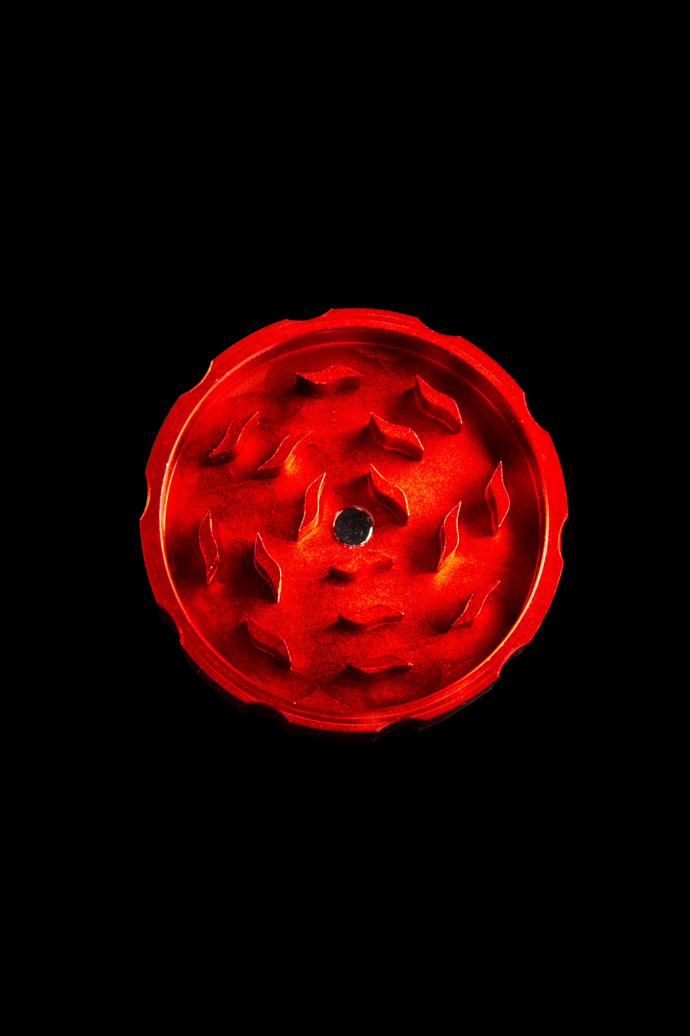 Red cannabis grinder against a black background.