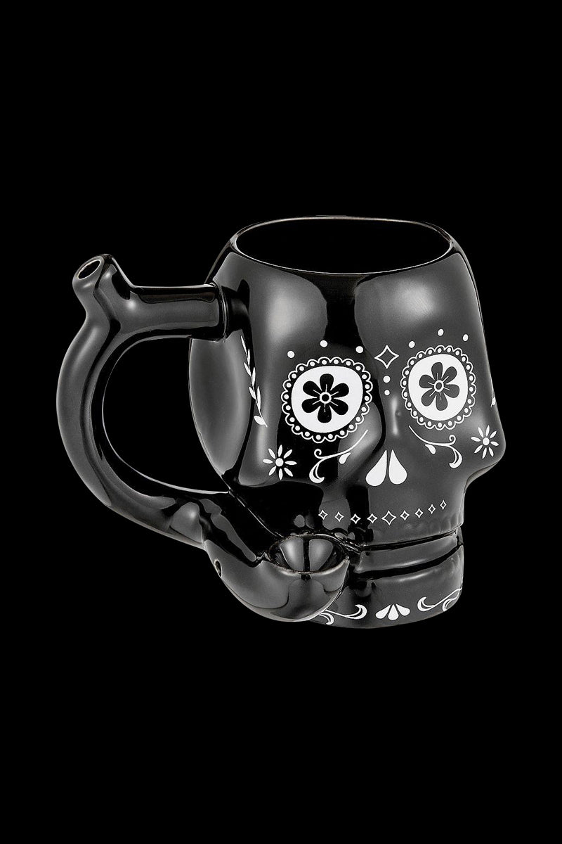 Three-quarter view of the Roast & Toast "Sugar Skull" Ceramic Pipe Mug in glossy black with white sugar-skull floral face art and a pipe-style handle.