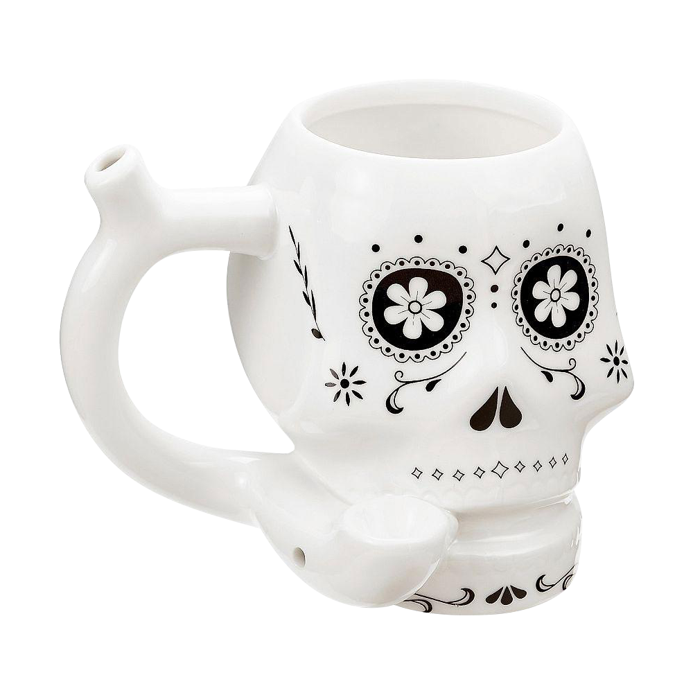 Three-quarter view of the Roast & Toast "Sugar Skull" Ceramic Pipe Mug showing its white skull shape, black floral eye designs, side handle stem, and front bowl.