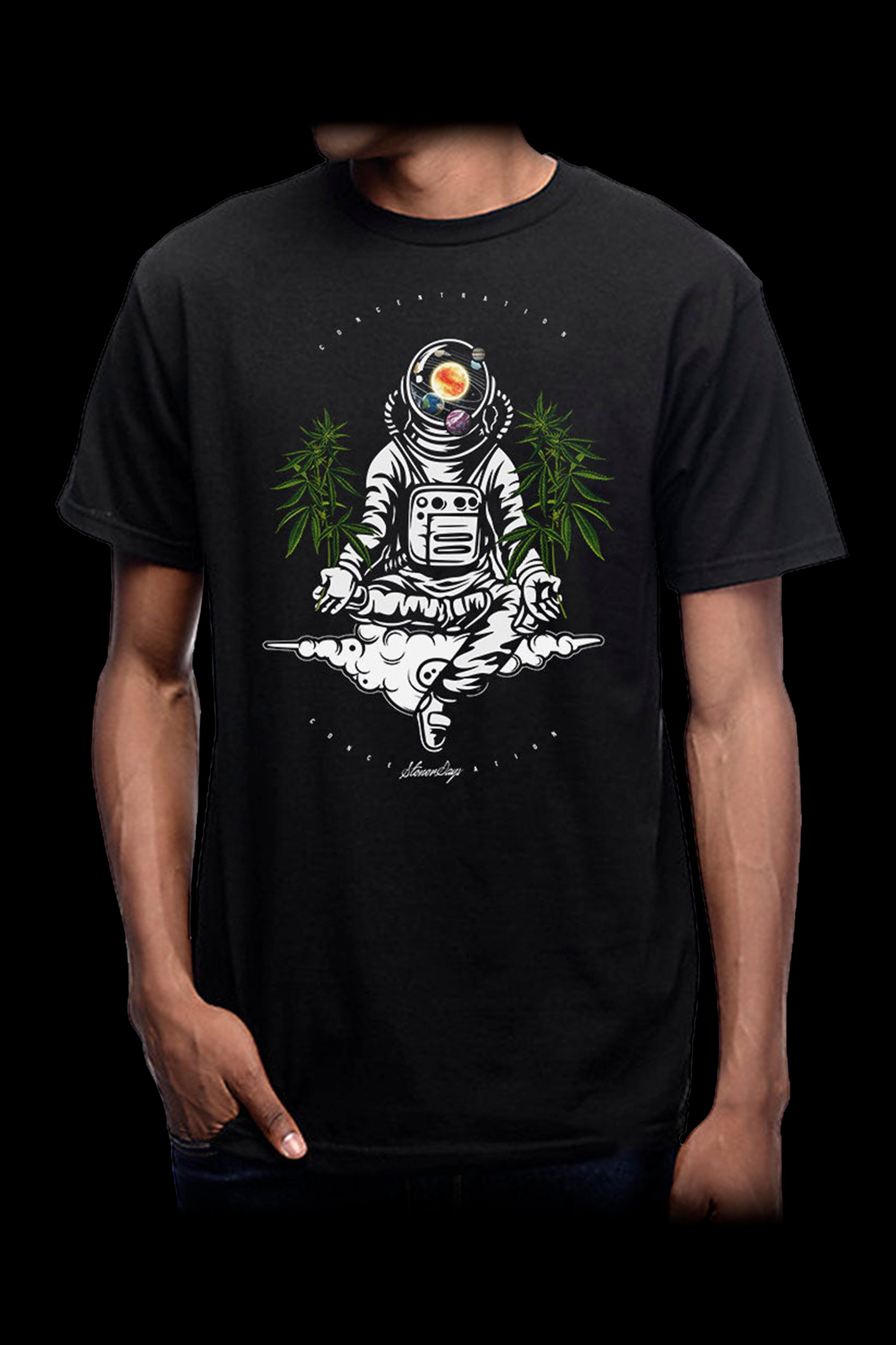 A man wearing a black t-shirt featuring a detailed illustration of an astronaut in a meditative pose surrounded by cannabis leaves.
