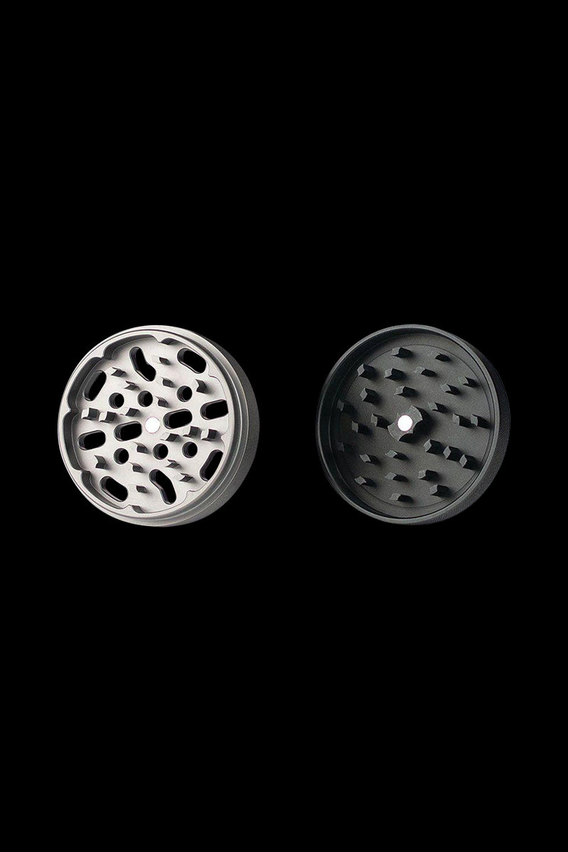 A top-down view of the Kannastor 4-Piece Solid Body Grinder, showcasing its metallic, multi-tiered design against a dark backdrop.