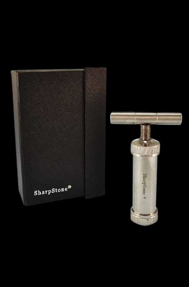 Close-up of the Sharpstone T-Style Press with Case showing the small silver T-handle press beside its black textured box on a black background.