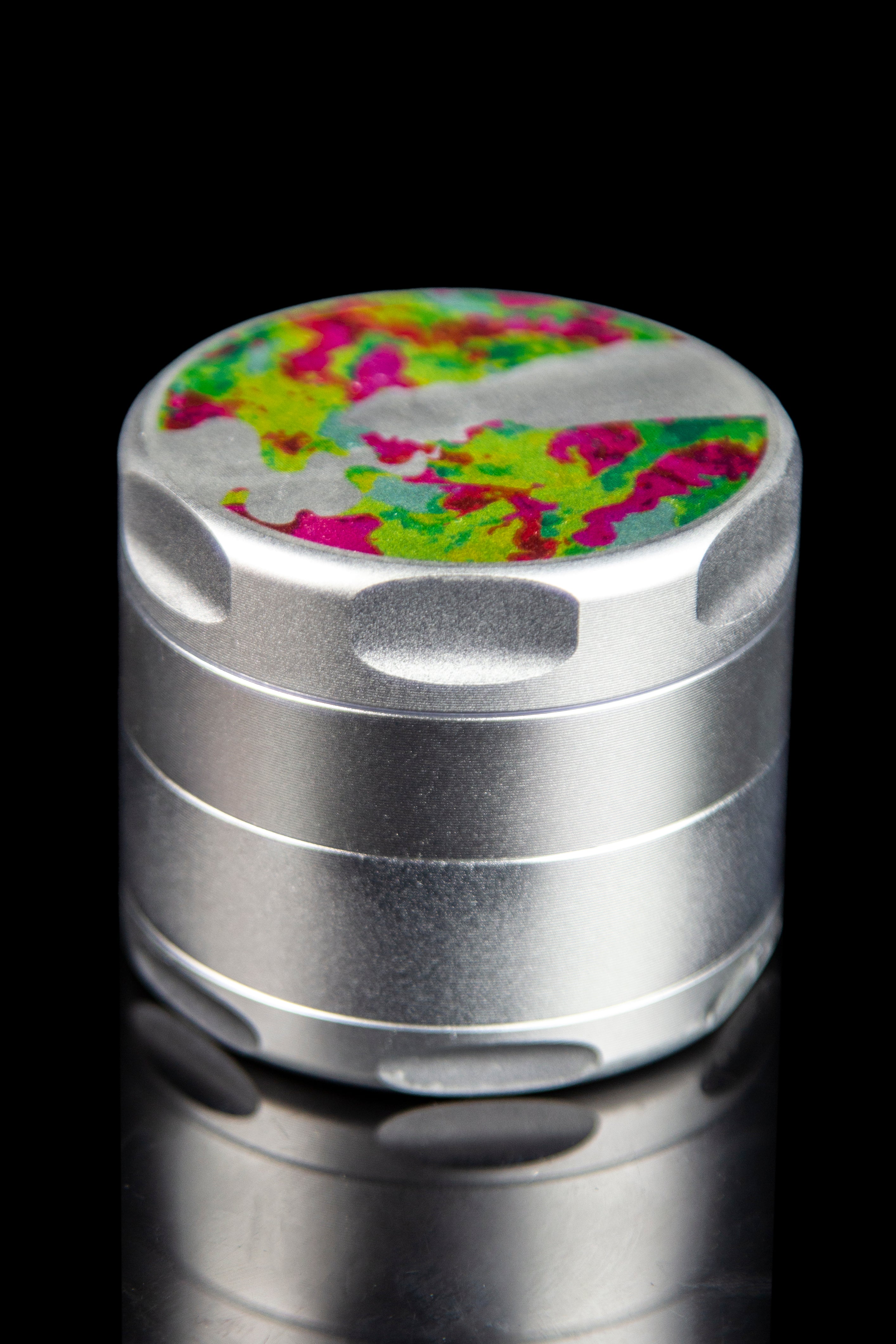 Silver cannabis grinder with a colorful, patterned top.