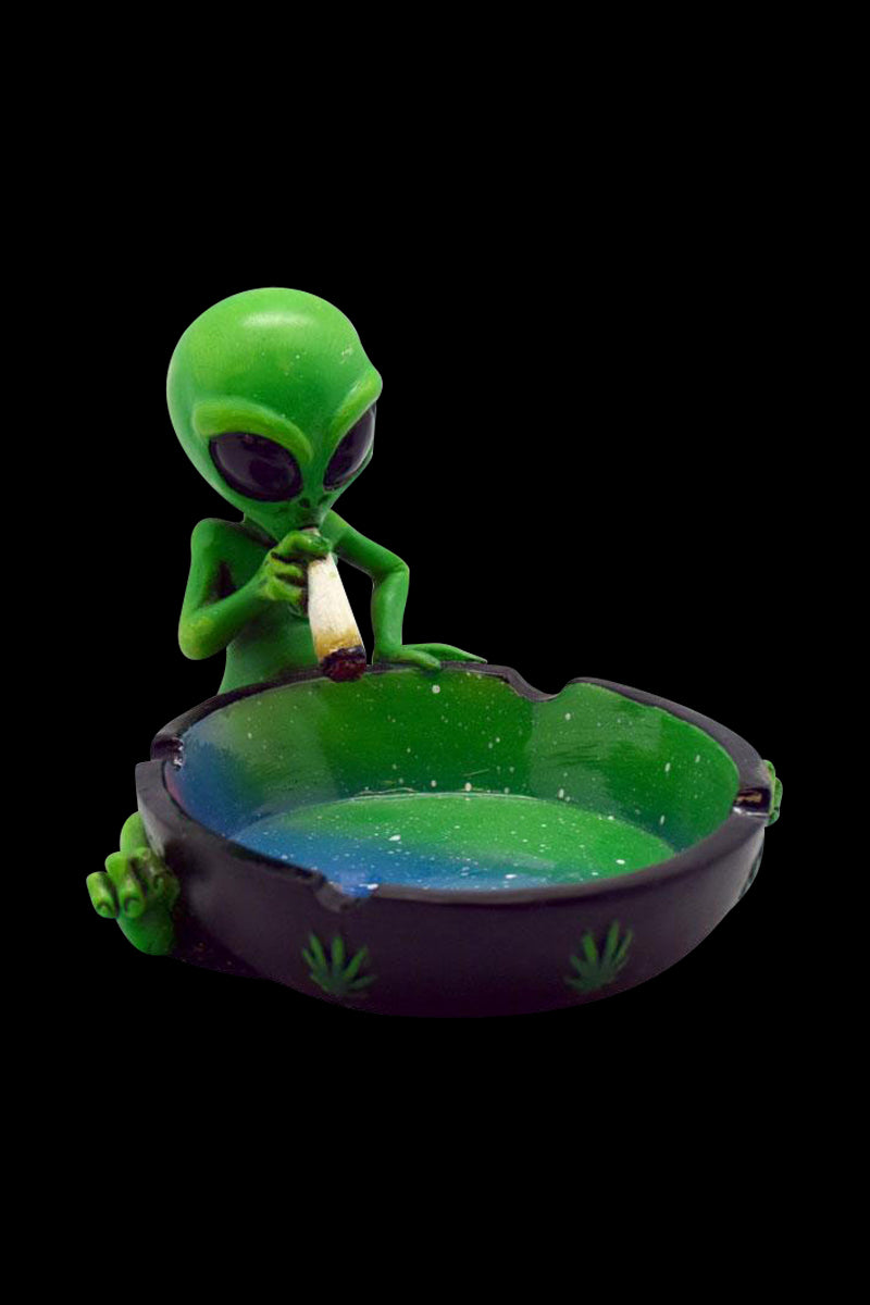A close-up of the Smoking Alien Ashtray, showing a green alien figure holding a dish, captured with dramatic lighting.