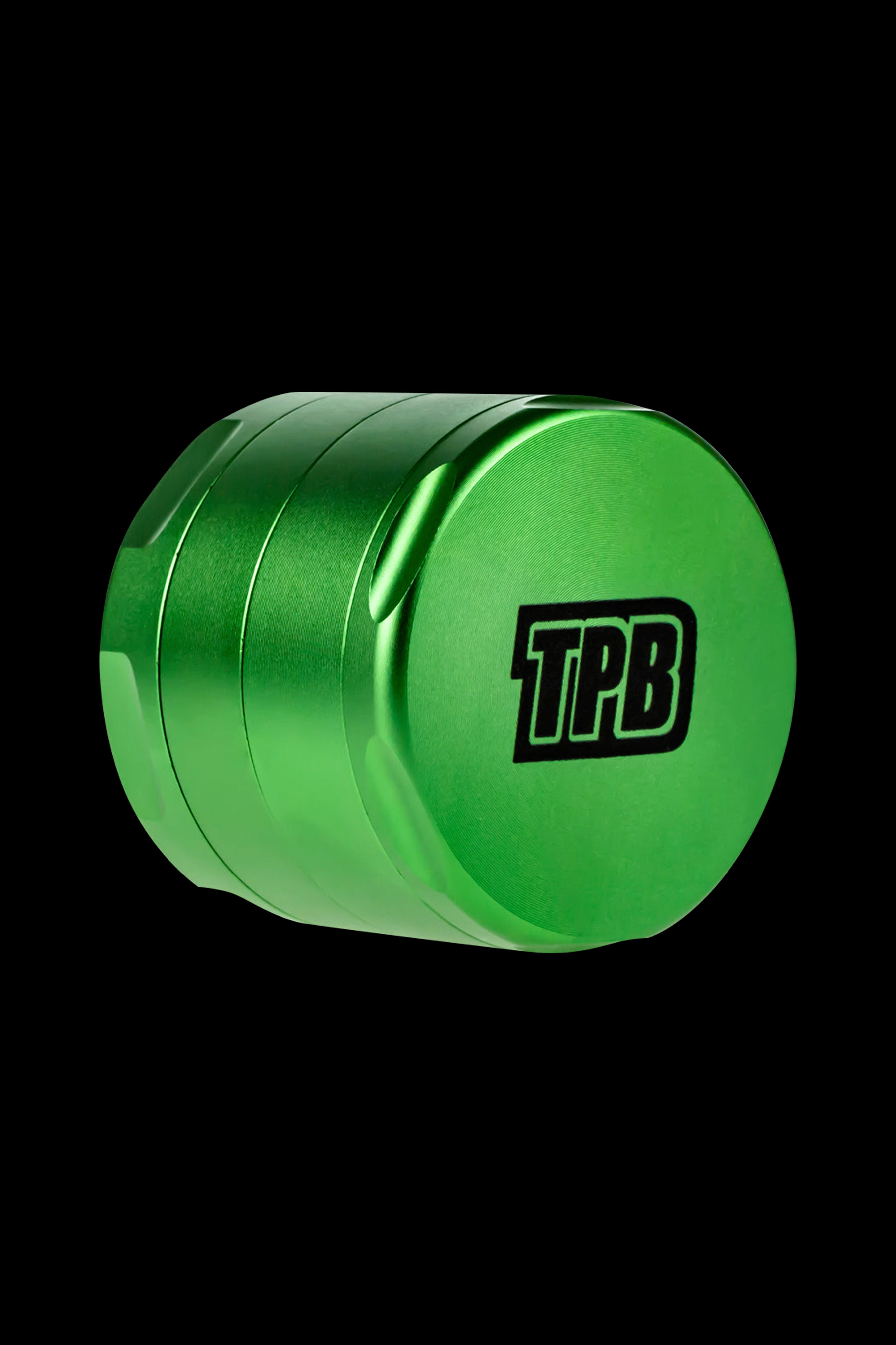 Green four-piece metal grinder with “TPB” logo, isolated on black.