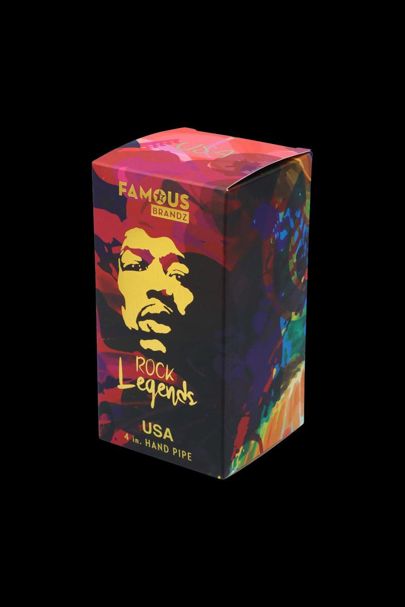 Three-quarter view of the colorful Famous Brandz "Rock Legends "Jimi USA" Spoon Pipe" box with a stylized yellow face on a red and purple background.