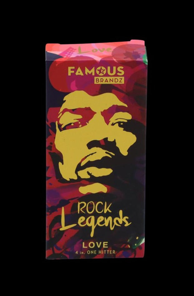 Front-facing image of the Rock Legends "Jimi Love" Aluminum Dugout box with a stylized yellow face on red and purple swirls and "Famous Brandz" logo at top.