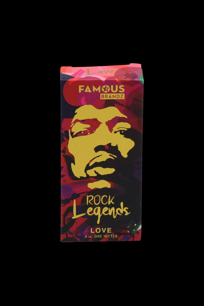 Front-facing image of the Rock Legends "Jimi Love" Aluminum Dugout box with a bold yellow stylized face on a red and purple patterned background.