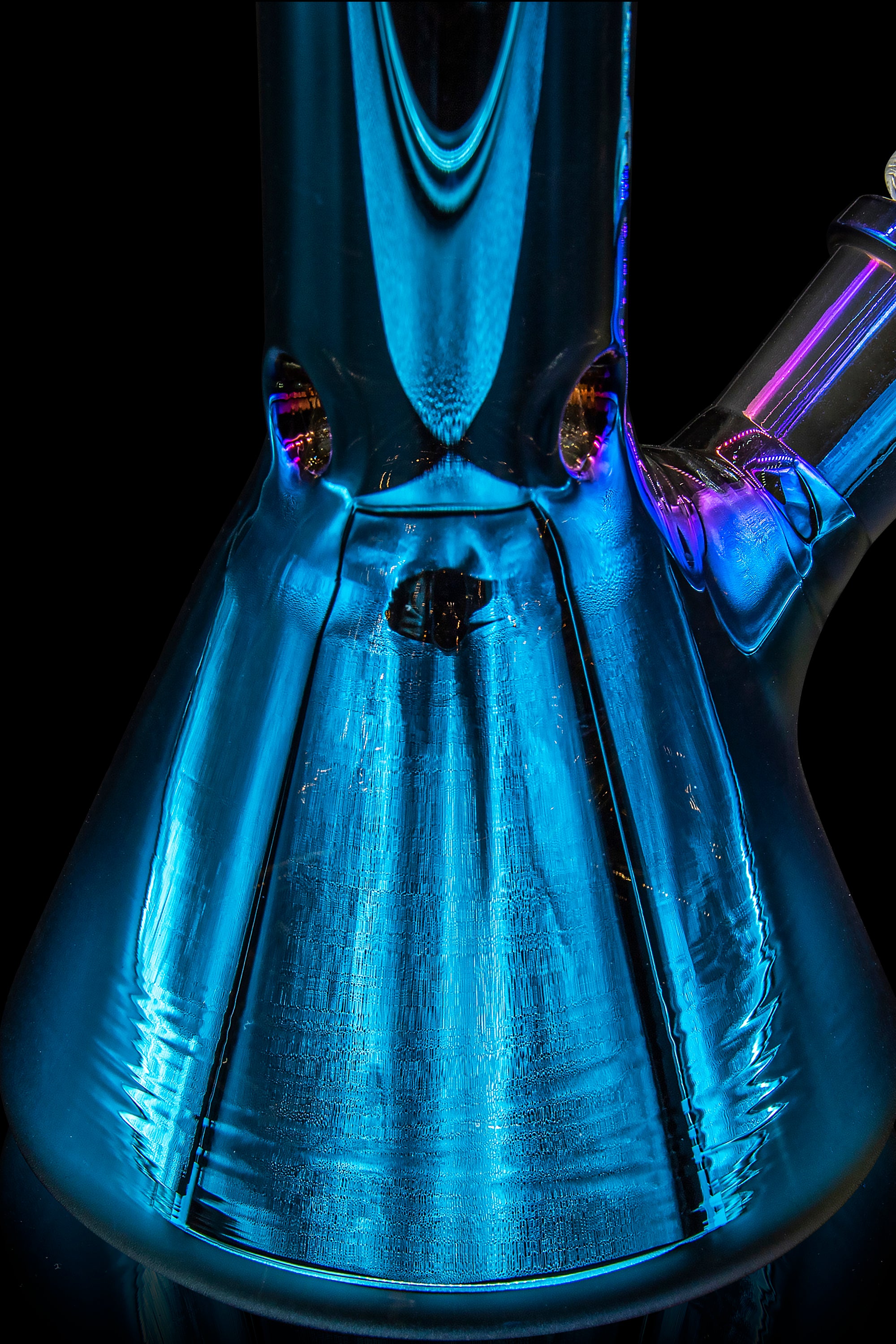 Blue glass bong illuminated with purple and gold light, viewed from within the bowl.