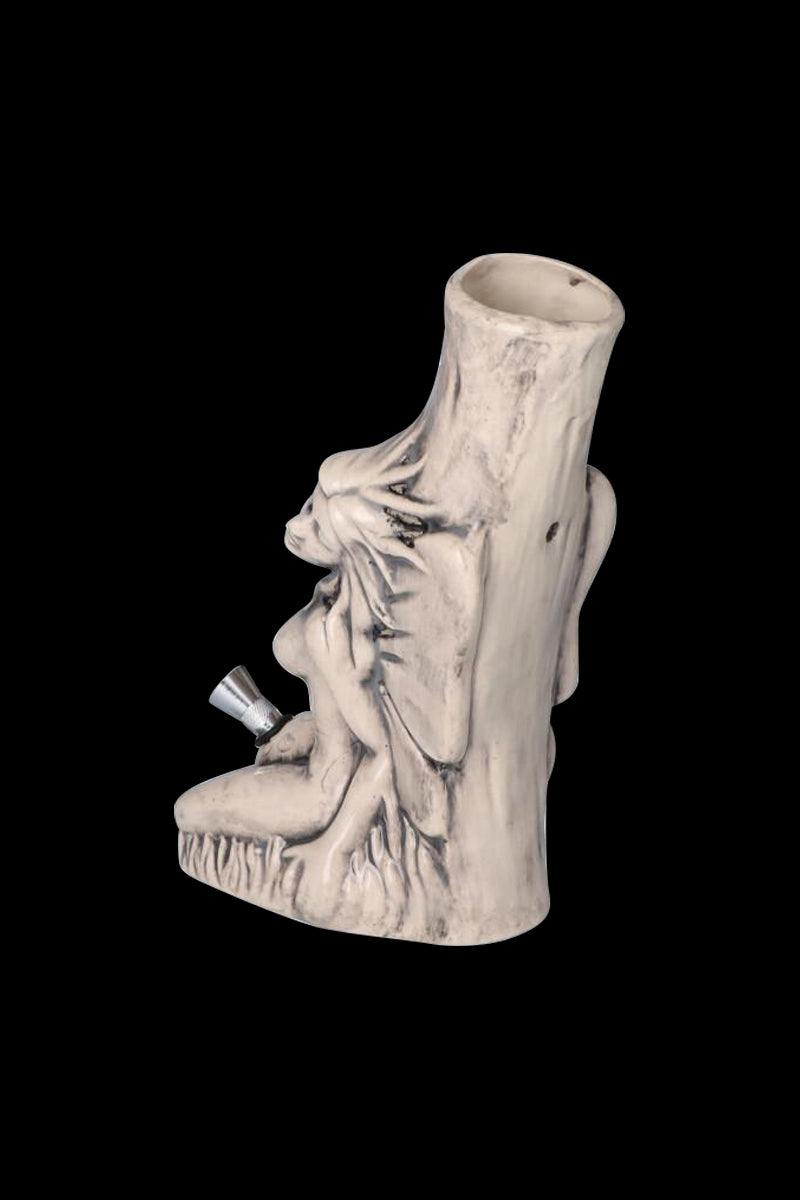 Three-quarter view of the Sleeping Maiden with Water Jug Ceramic Pipe showing a pale, carved maiden reclining against a hollow tree trunk on a black background.