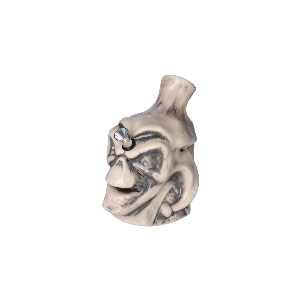 Angled front view of the Smiling Skull Ceramic Pipe showing a weathered white skull face with dark accents and a metal bowl in the forehead