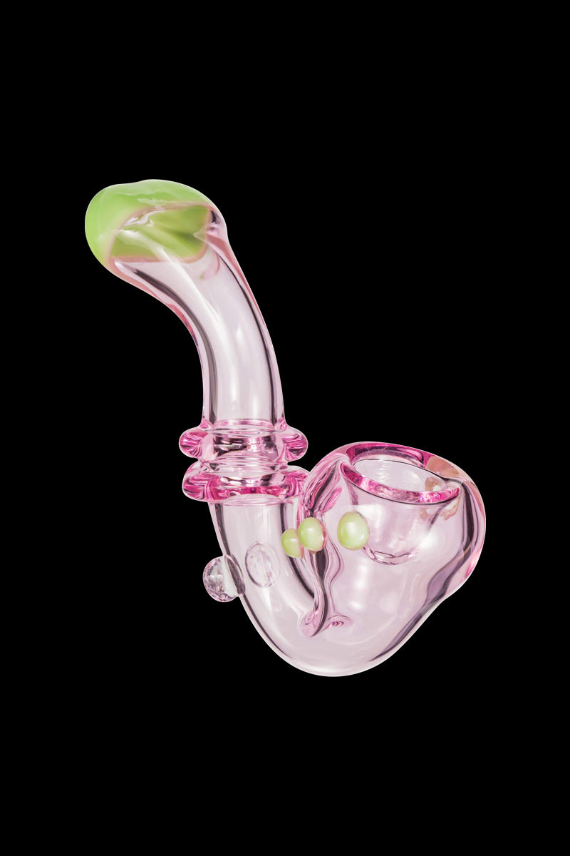 Angled close-up of the Maria Ring Sherlock Pipe showing a translucent pink glass body with a curved stem and lime-green mouthpiece and accent beads against a black background.